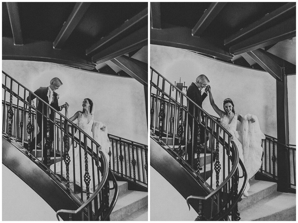 woman in suit holding hand of woman in white wedding dress as they run down romantic staircase