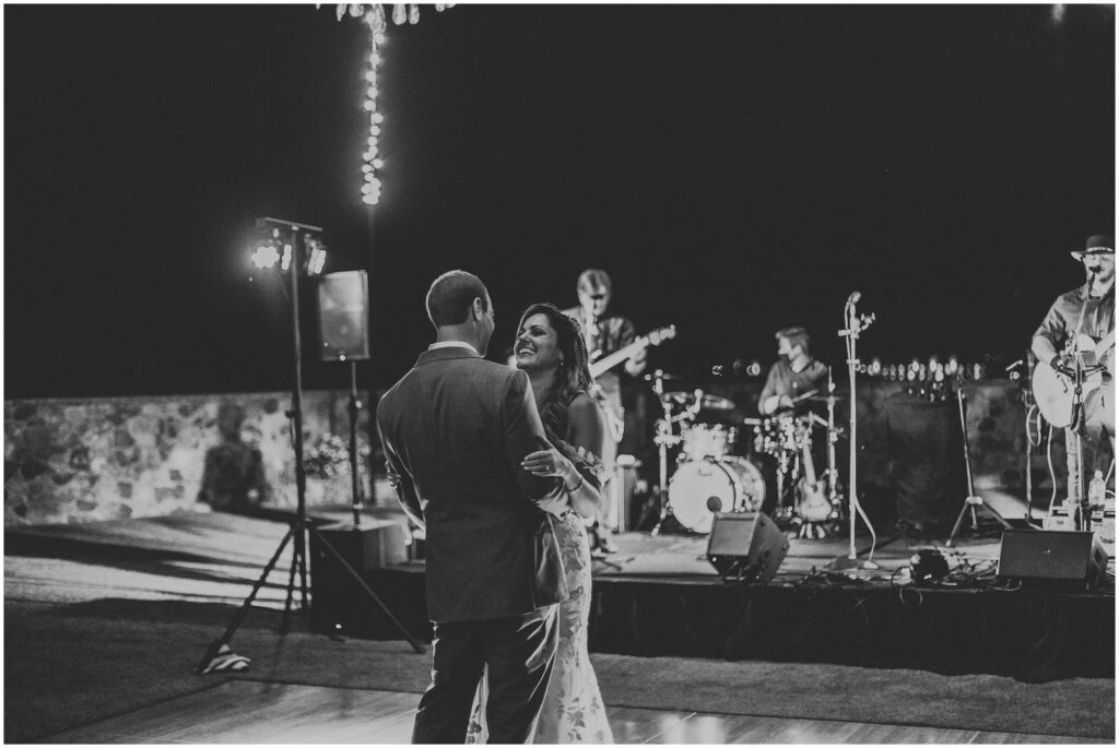 black-and-white photo of bride and groom sharing first dance at outdoor Orlando wedding while wedding band plays in the background