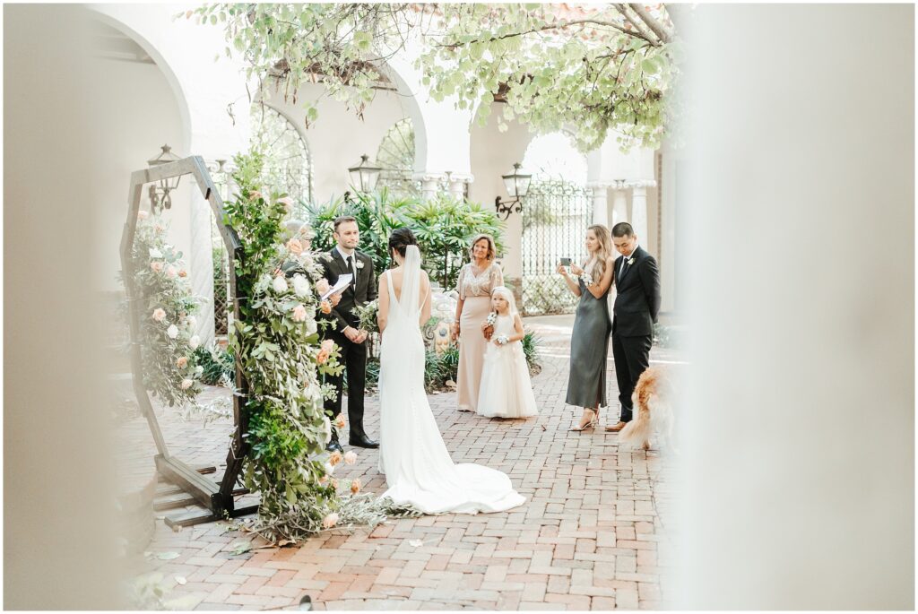 romantic photo of bride and groom at altar during outdoor garden wedding surrounded by roses and and green vines