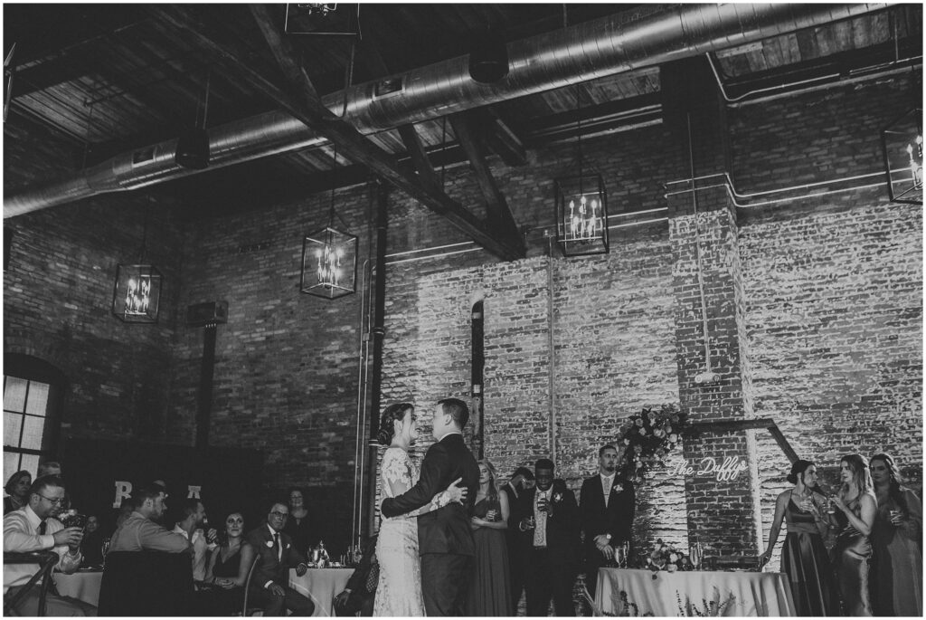 Black and white photo of bride and groom in embrace while sharing first dance at Armature Works in Tampa Florida