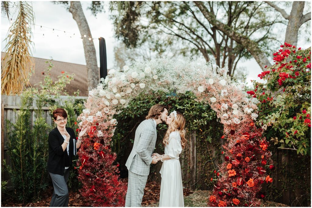 Bride and groom share first kiss at altar with autumn inspired wedding colors 
