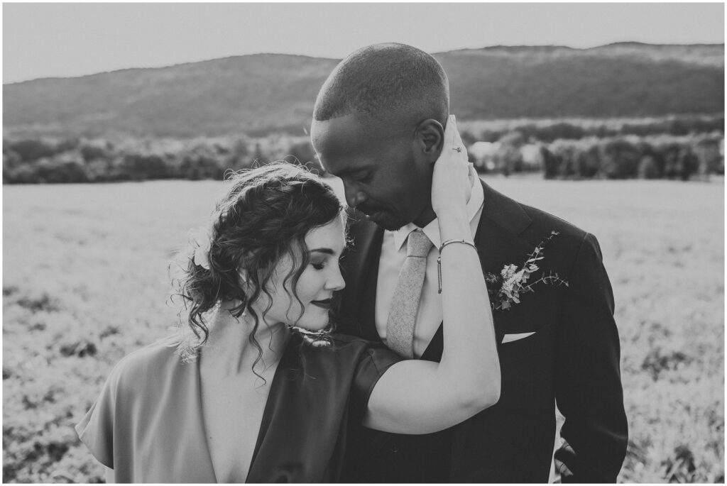 romantic, black and white portrait of bride with arm wrapped around groom's neck as they both smile 