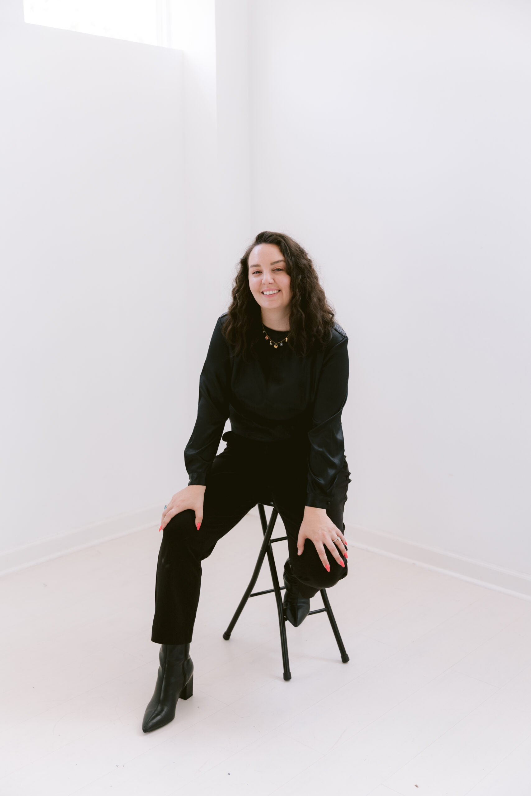 Ashley Izquierdo, Tampa elopement photographer, sitting confidently in a bright downtown studio