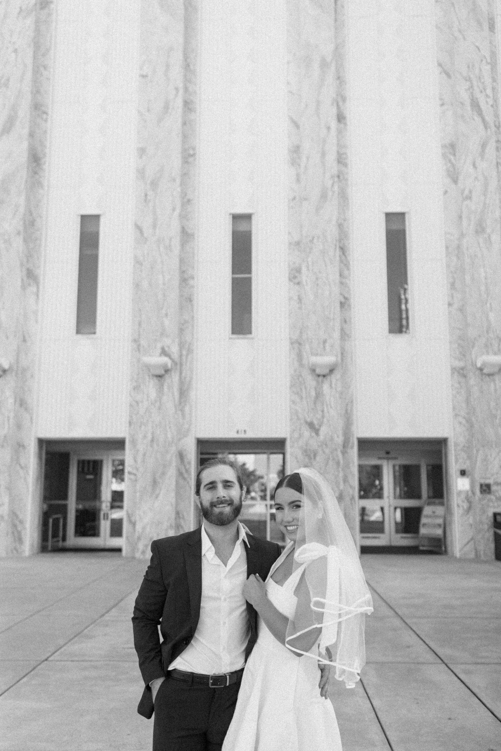 Bride and groom stand smiling outside the Hillsborough County courthouse after their elopement ceremony in Tampa