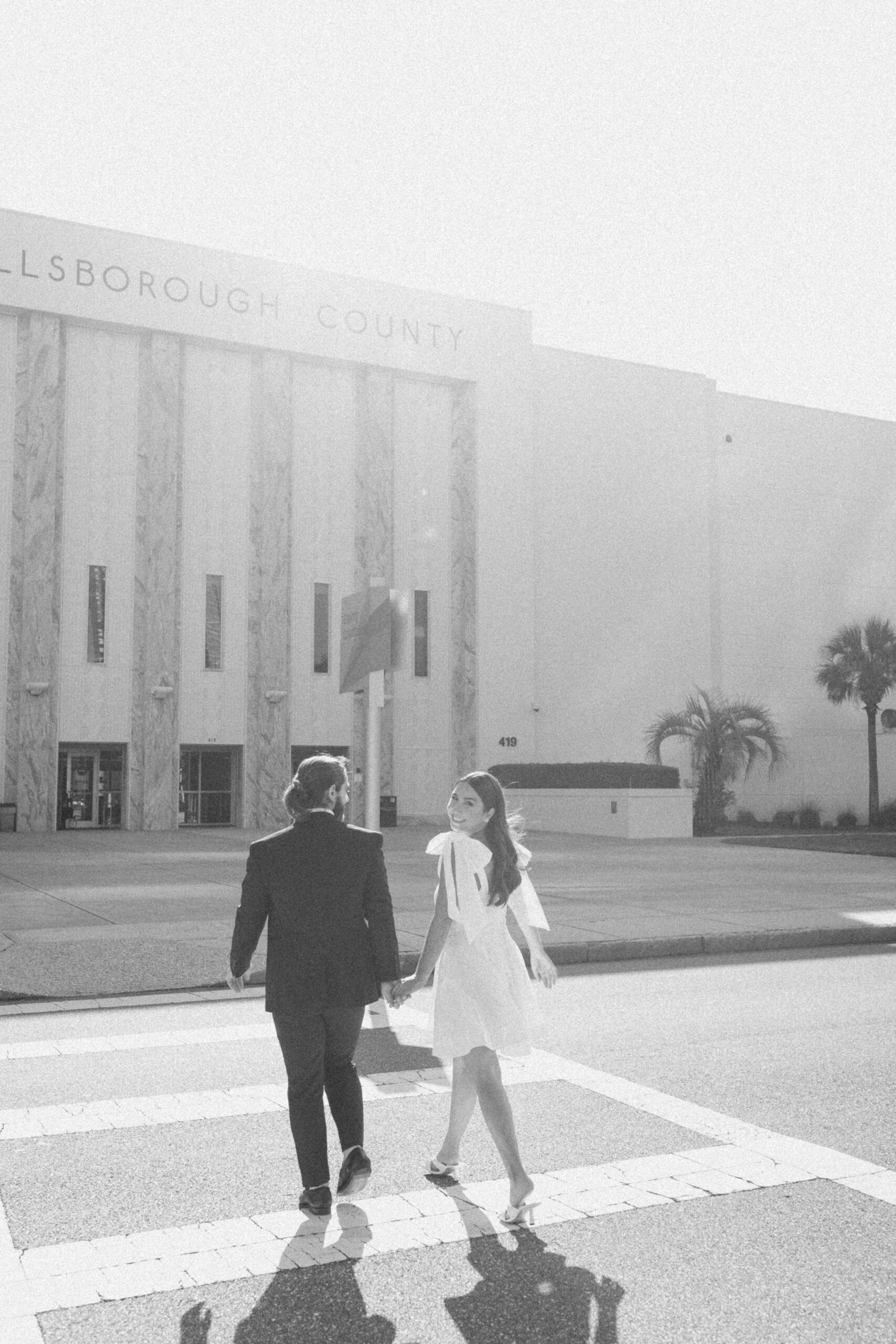 Bride and groom walk hand in hand across the street after their Hillsborough County courthouse wedding