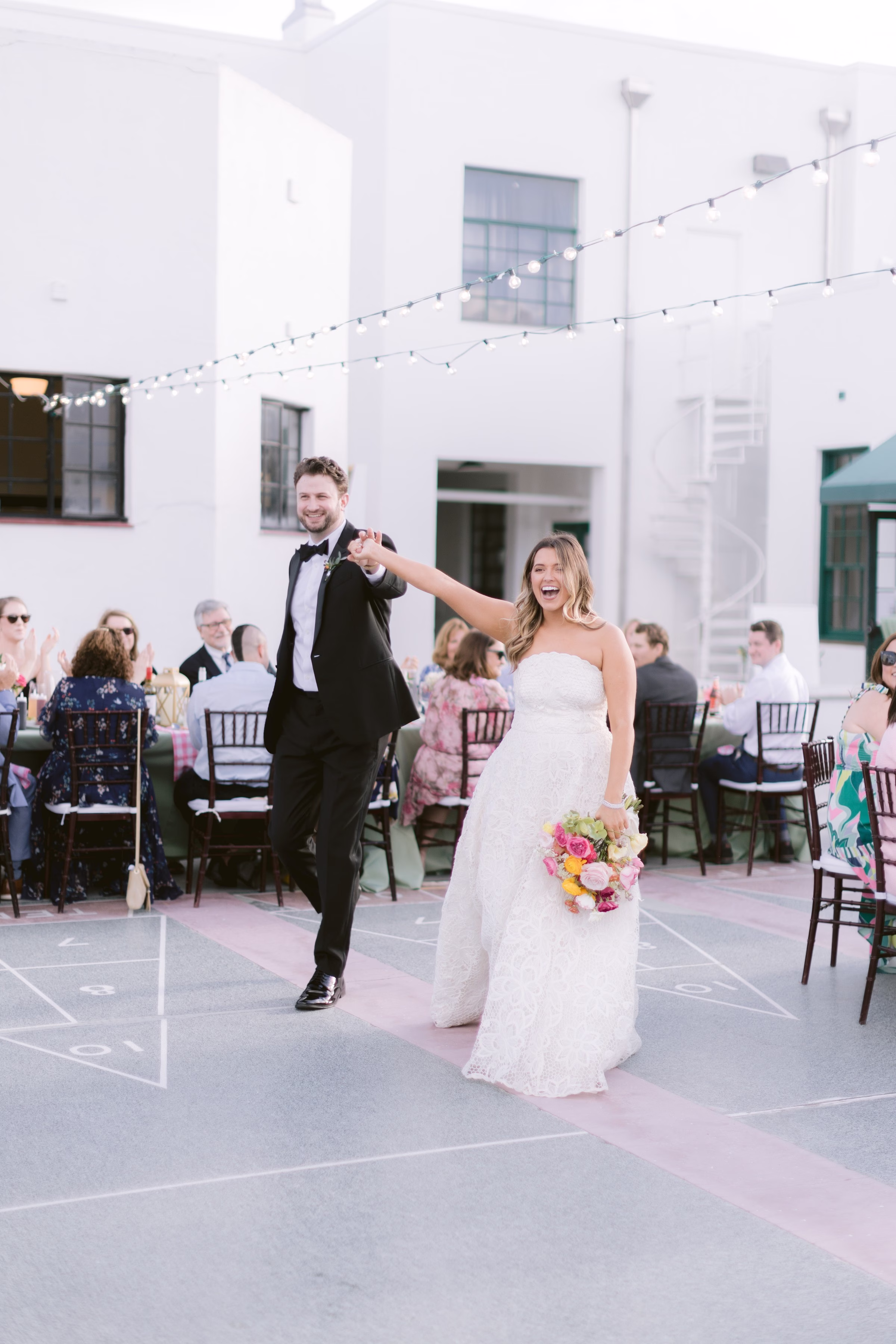 Bride and groom celebrate their first dance at outdoor wedding reception in Tampa Bay courtyard with string lights and guests