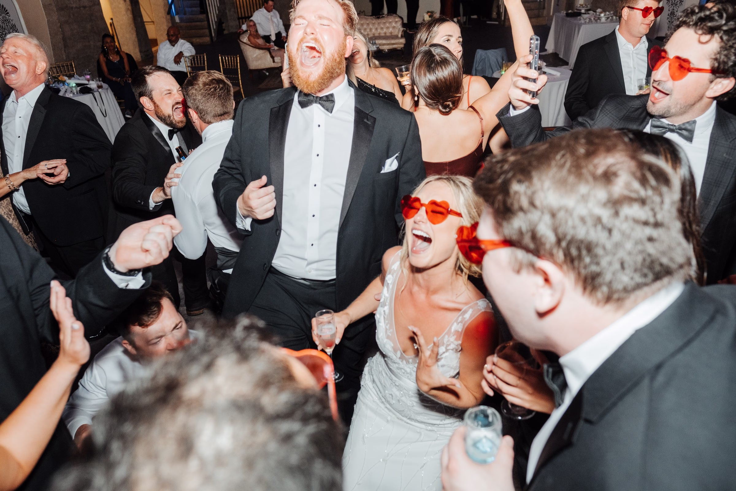Bride and groom dancing with wedding guests in formal attire during energetic Tampa Bay wedding reception captured by Ashley Izquierdo Photography
