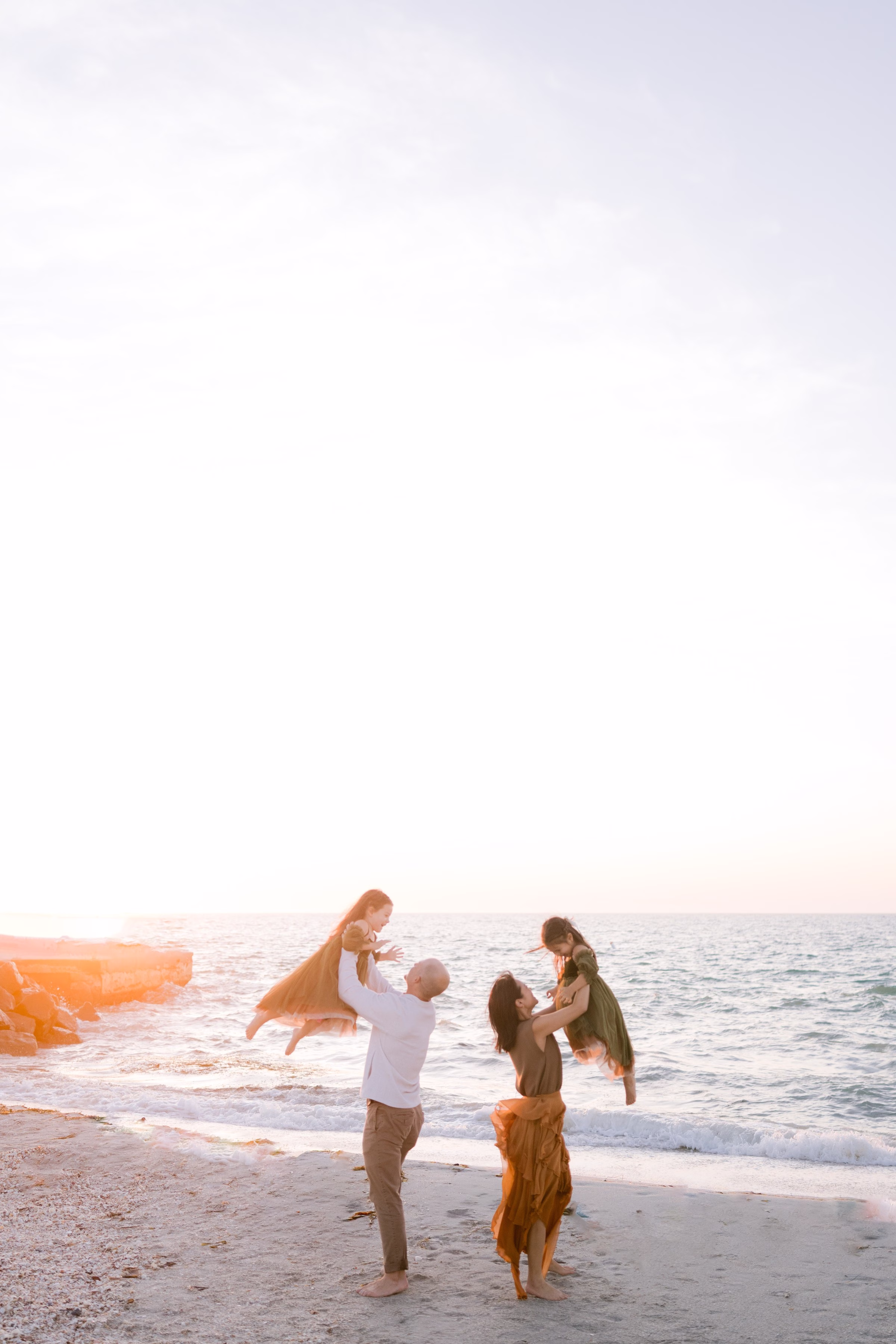 Family playing on Tampa Bay beach during golden hour sunset session by Ashley Izquierdo Photography