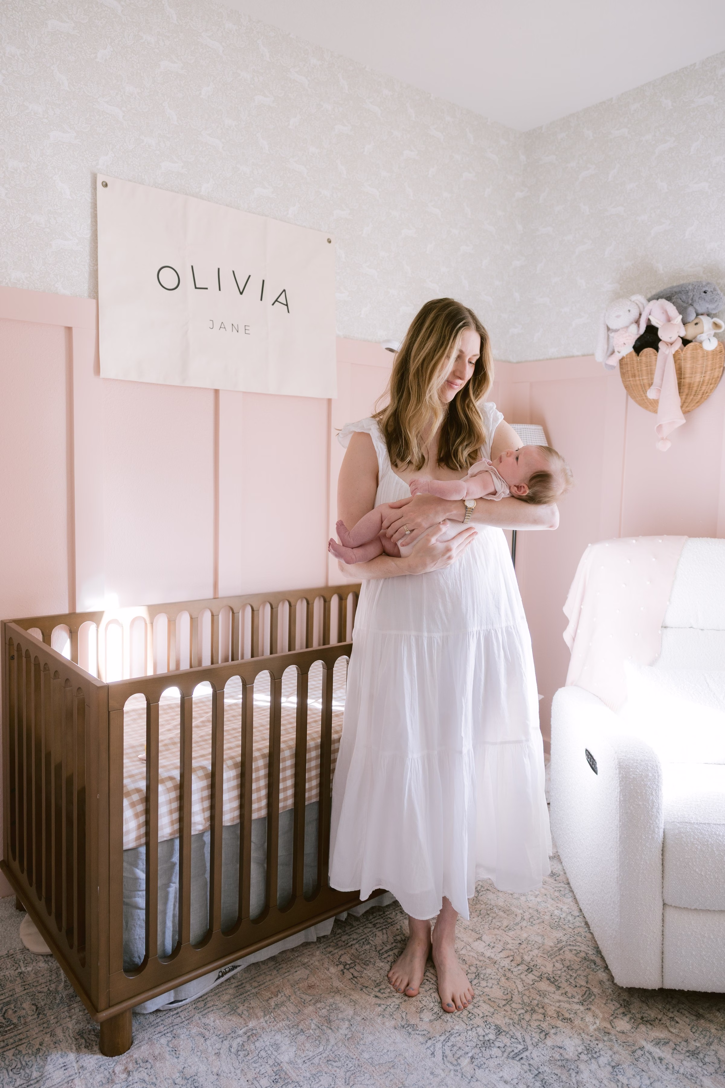 Tampa maternity and newborn photographer Ashley Izquierdo captures intimate moment between mother and baby in soft pink nursery