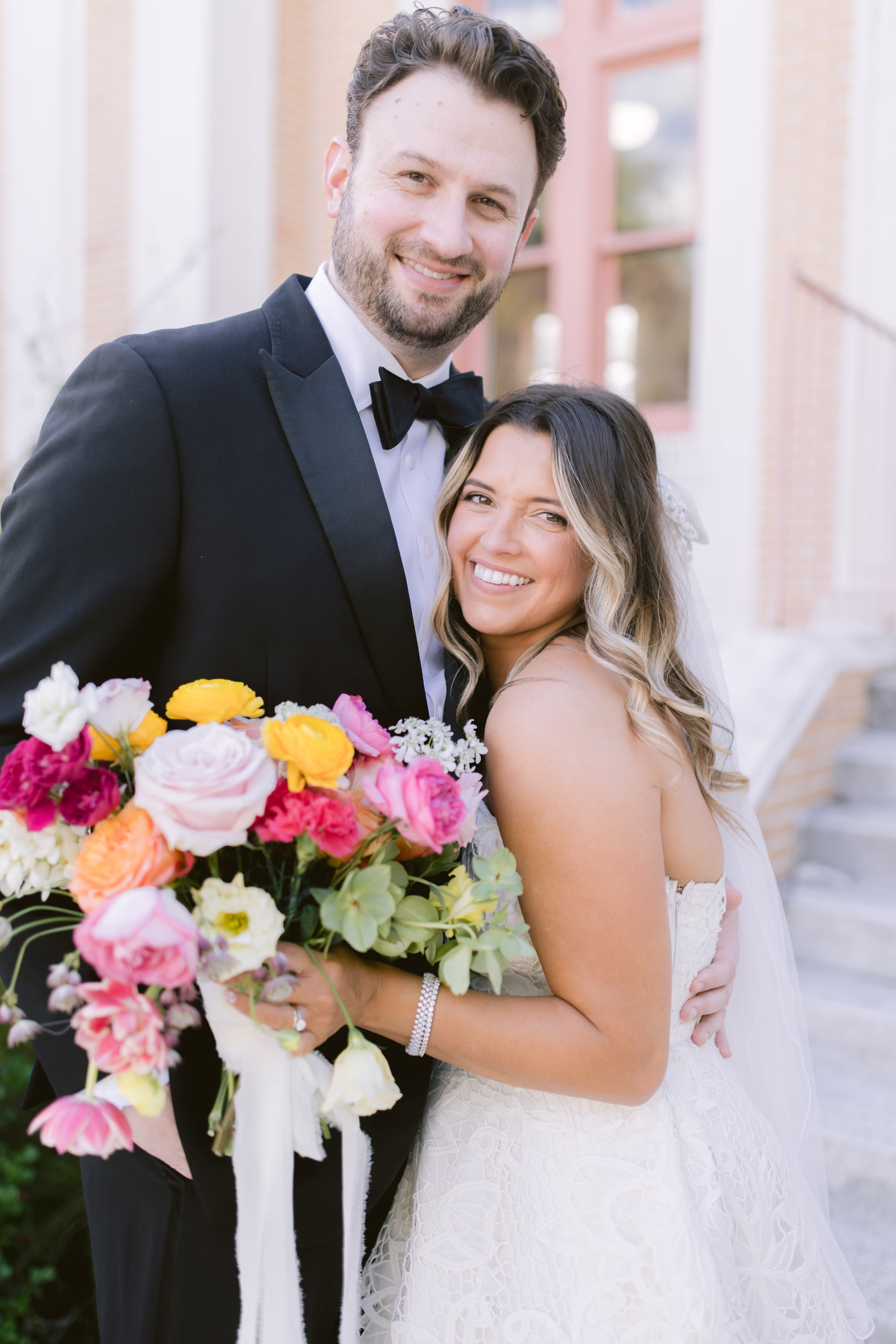 Bride and groom pose with vibrant colorful bouquet during downtown Tampa wedding portrait session by Ashley Izquierdo Photography