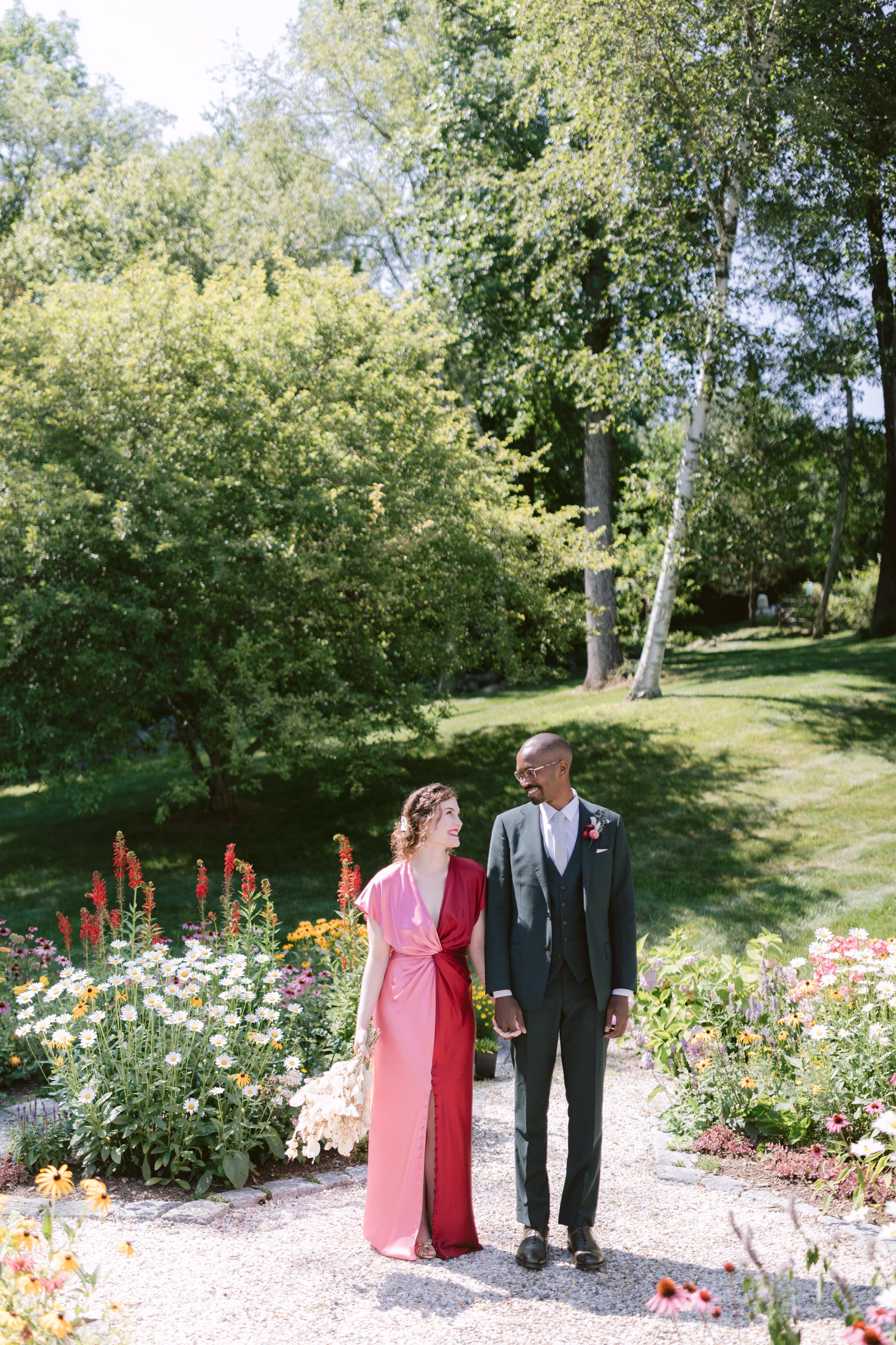 Elegant couple in formal attire walking through vibrant garden wedding venue with colorful flower beds in Tampa Bay