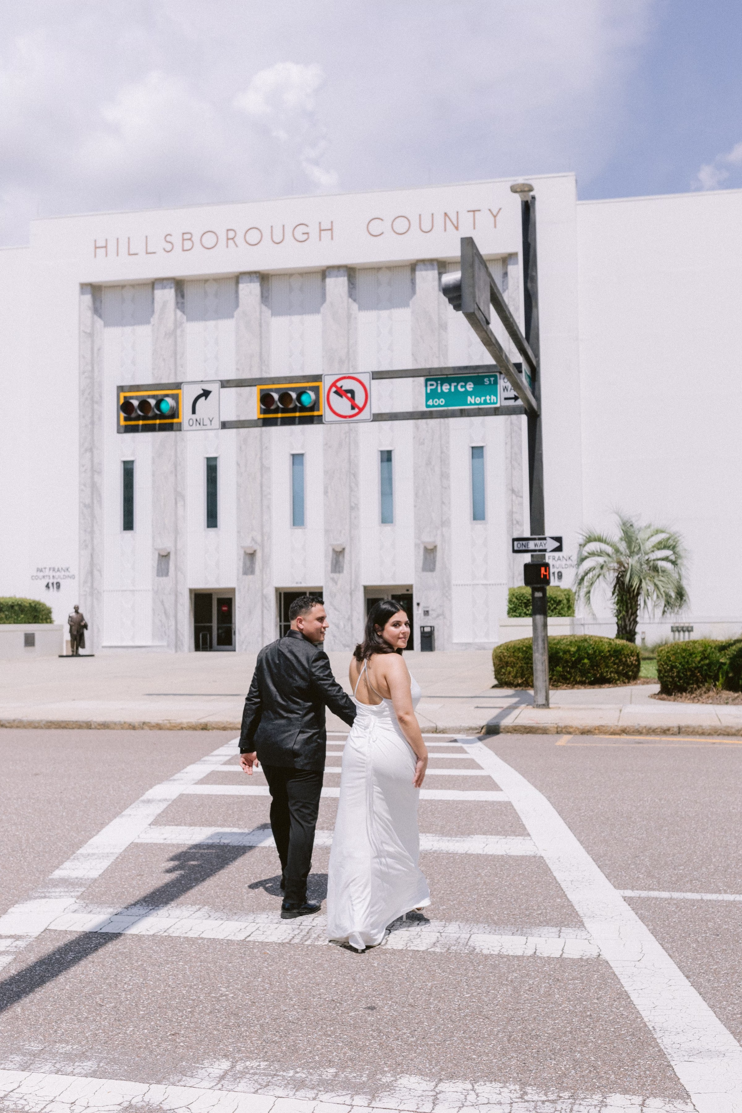 Bride and groom crossing street in front of Hillsborough County Courthouse during intimate Tampa elopement by Ashley Izquierdo Photography
