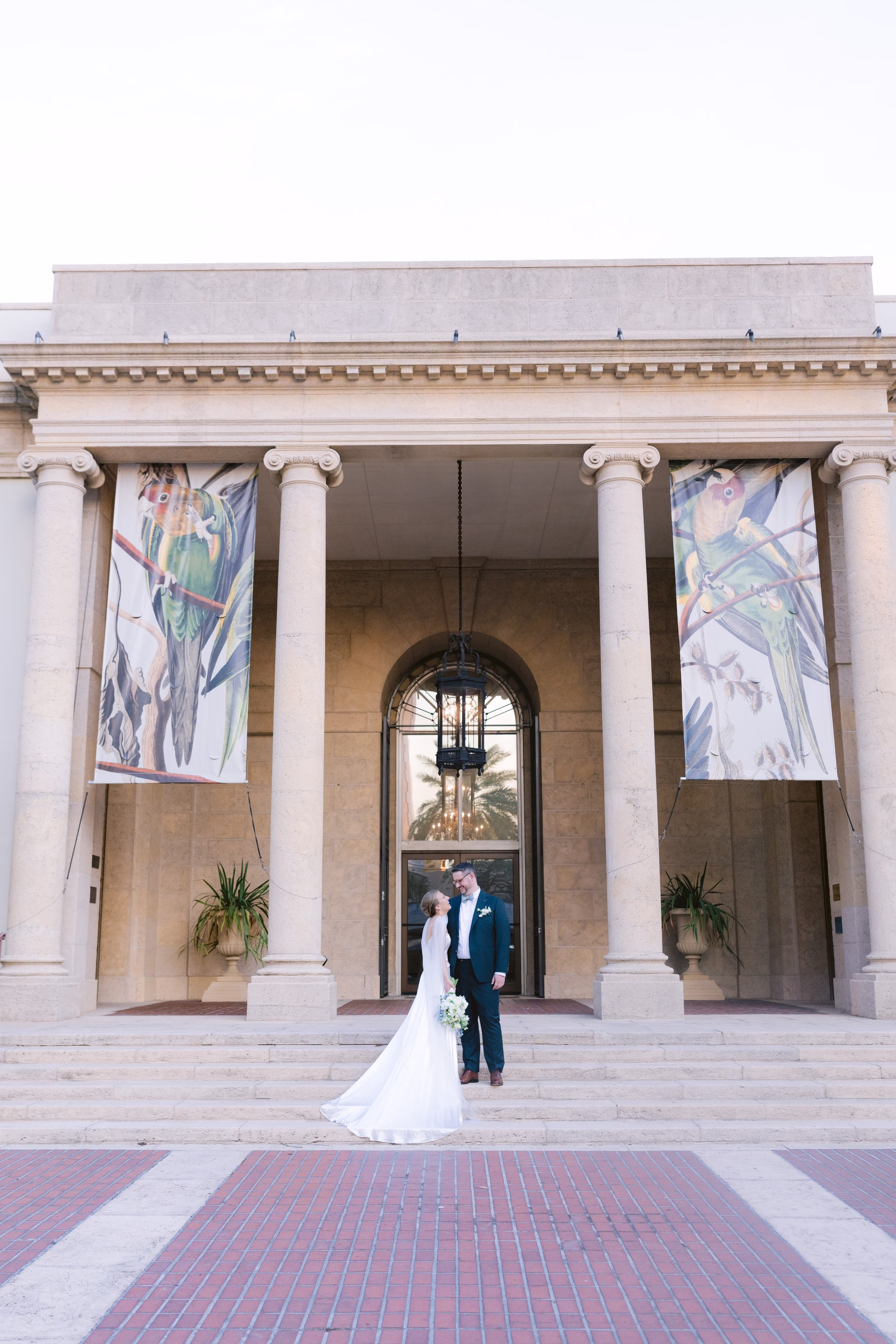 Bride and groom wedding portrait at Museum of Fine Arts St Pete featuring classical columns and colorful banners