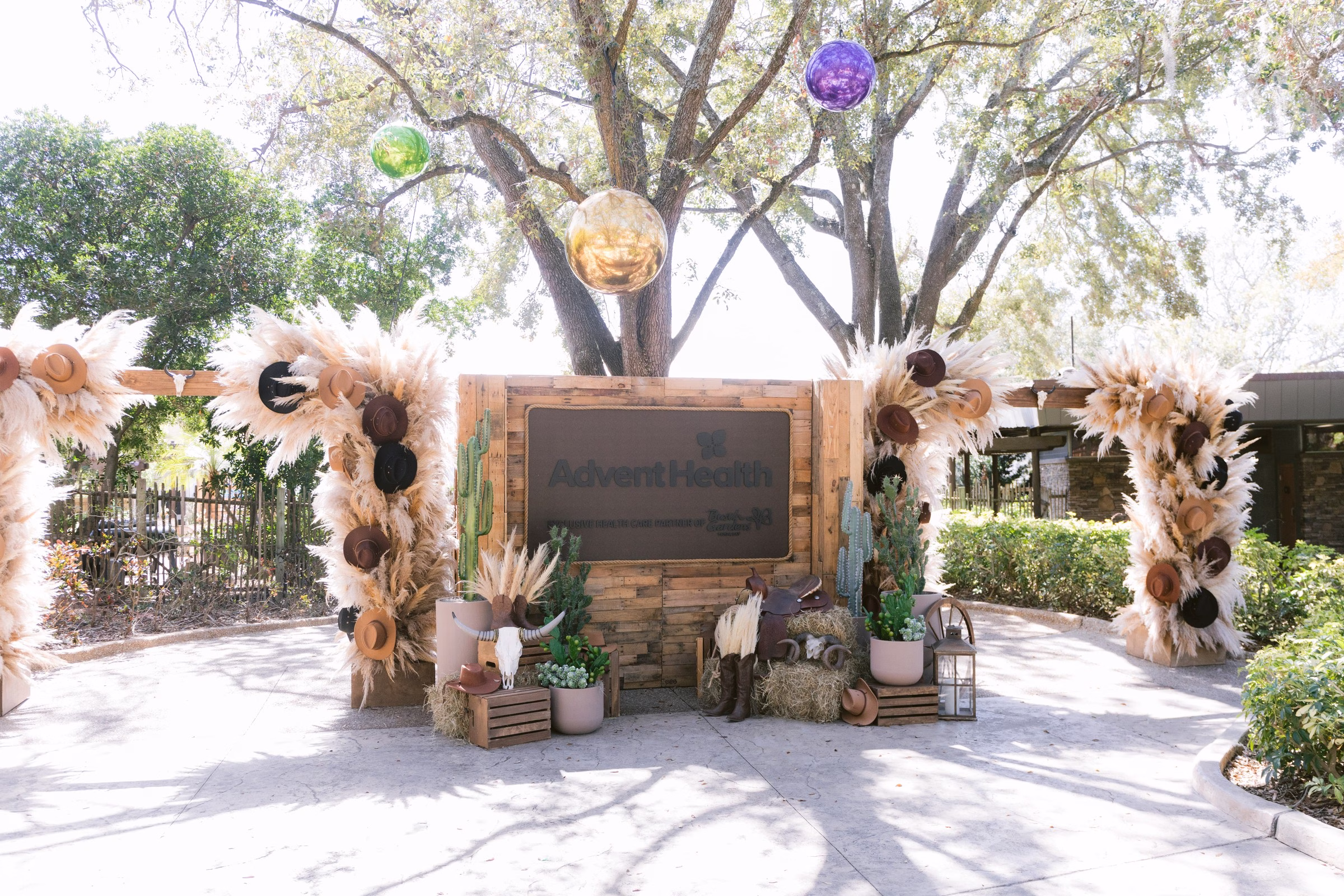 Elegant outdoor wedding backdrop with pampas grass florals and Advent Health signage at Tampa Bay venue photographed by Ashley Izquierdo Photography