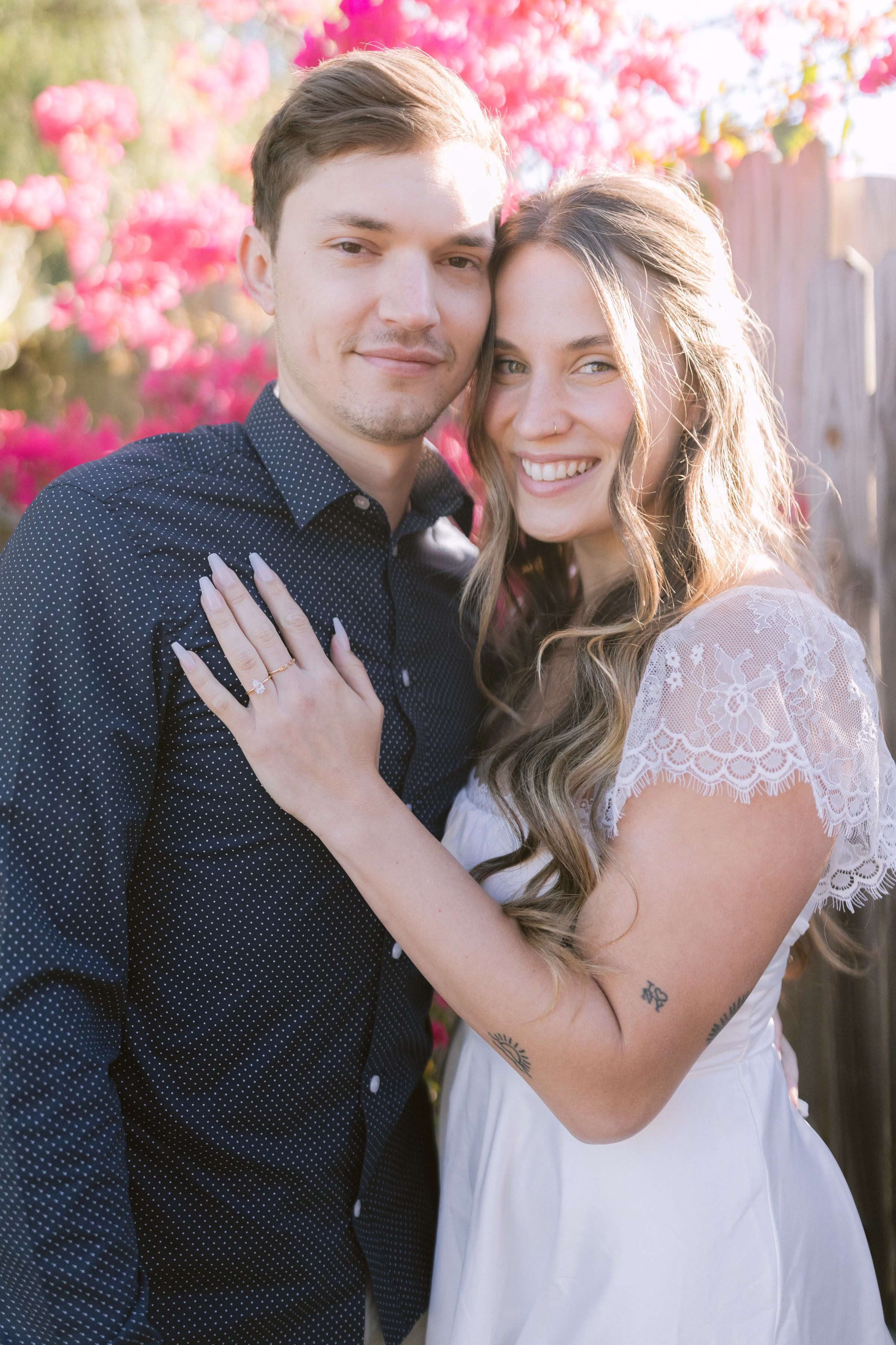 Romantic engagement portrait of couple embracing in Tampa Bay with vibrant pink flowering trees by Ashley Izquierdo Photography