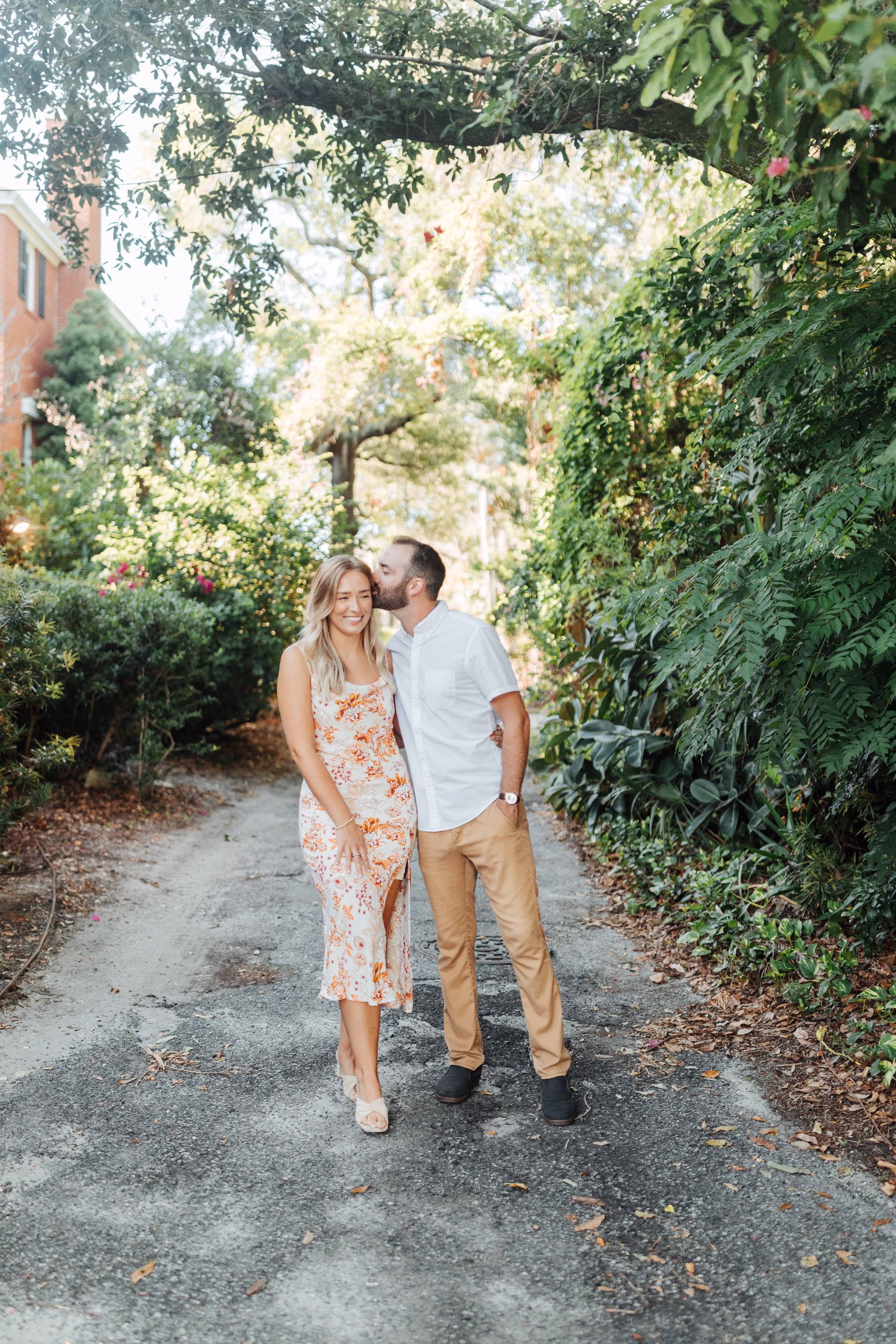 Romantic Tampa Bay engagement session with couple walking through lush garden pathway photographed by Ashley Izquierdo Photography