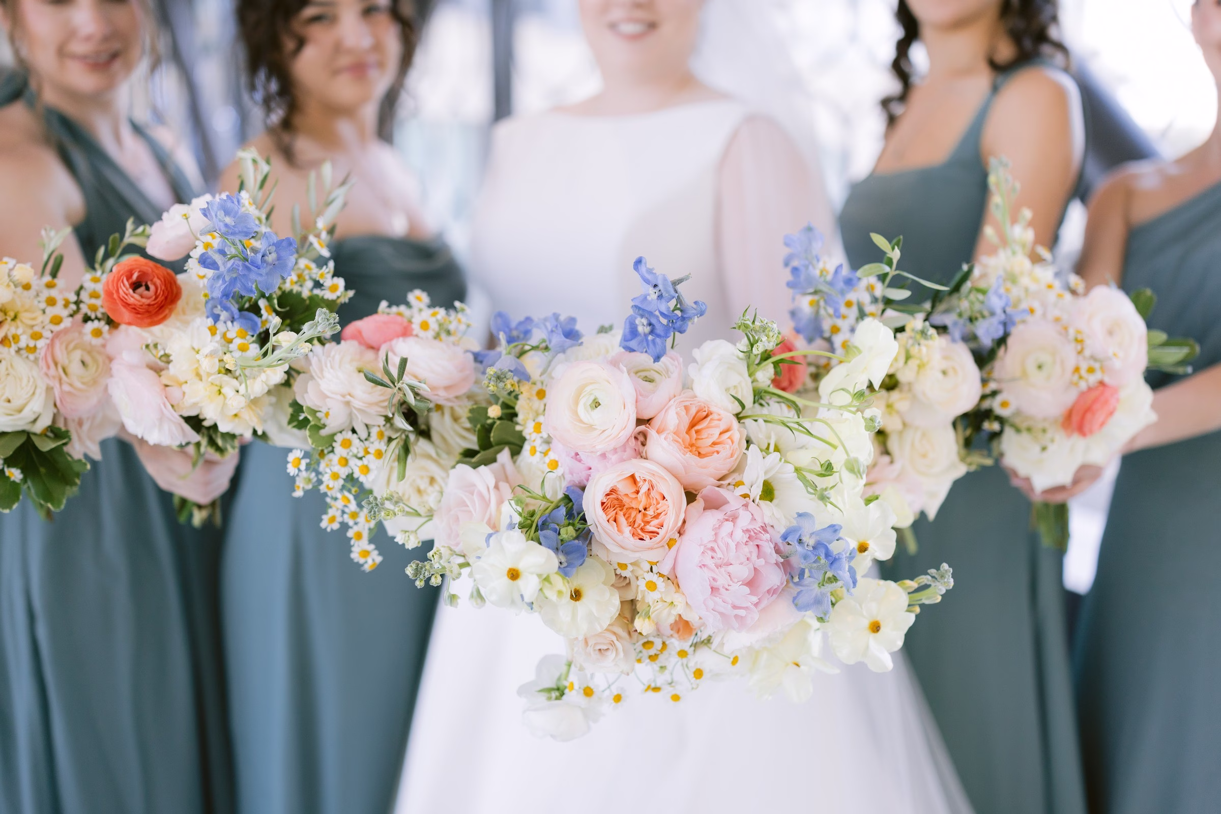 Tampa Bay wedding bridesmaids holding colorful spring bouquets with pink peonies, blue delphiniums, and white ranunculus photographed by Ashley Izquierdo Photography