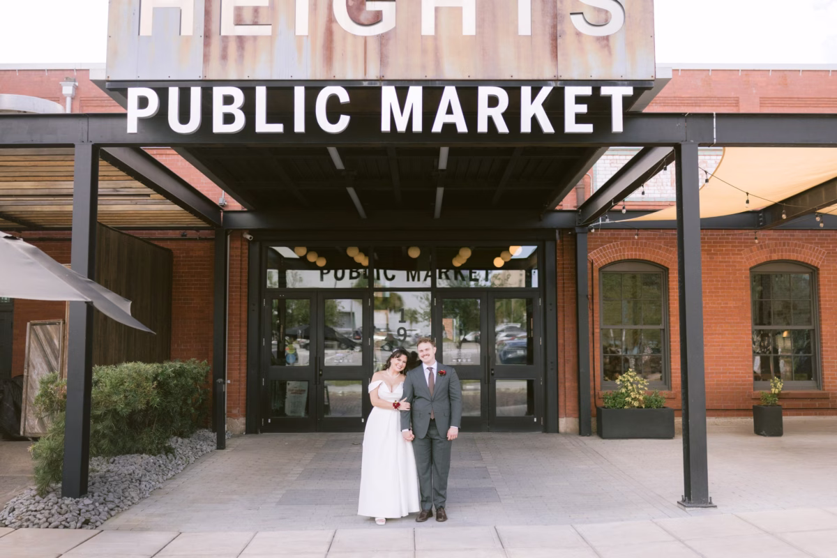 Bride and groom portrait at Armature Works Public Market entrance in Tampa featuring brick architecture and modern design