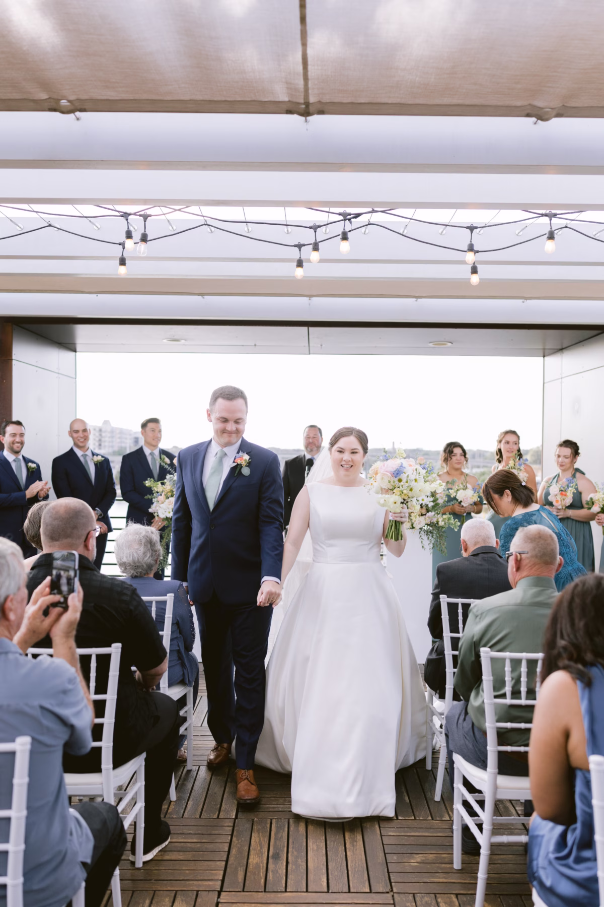 Bride and groom walking down the aisle after their wedding ceremony at Armature Works in Tampa with florals by I Dew Events