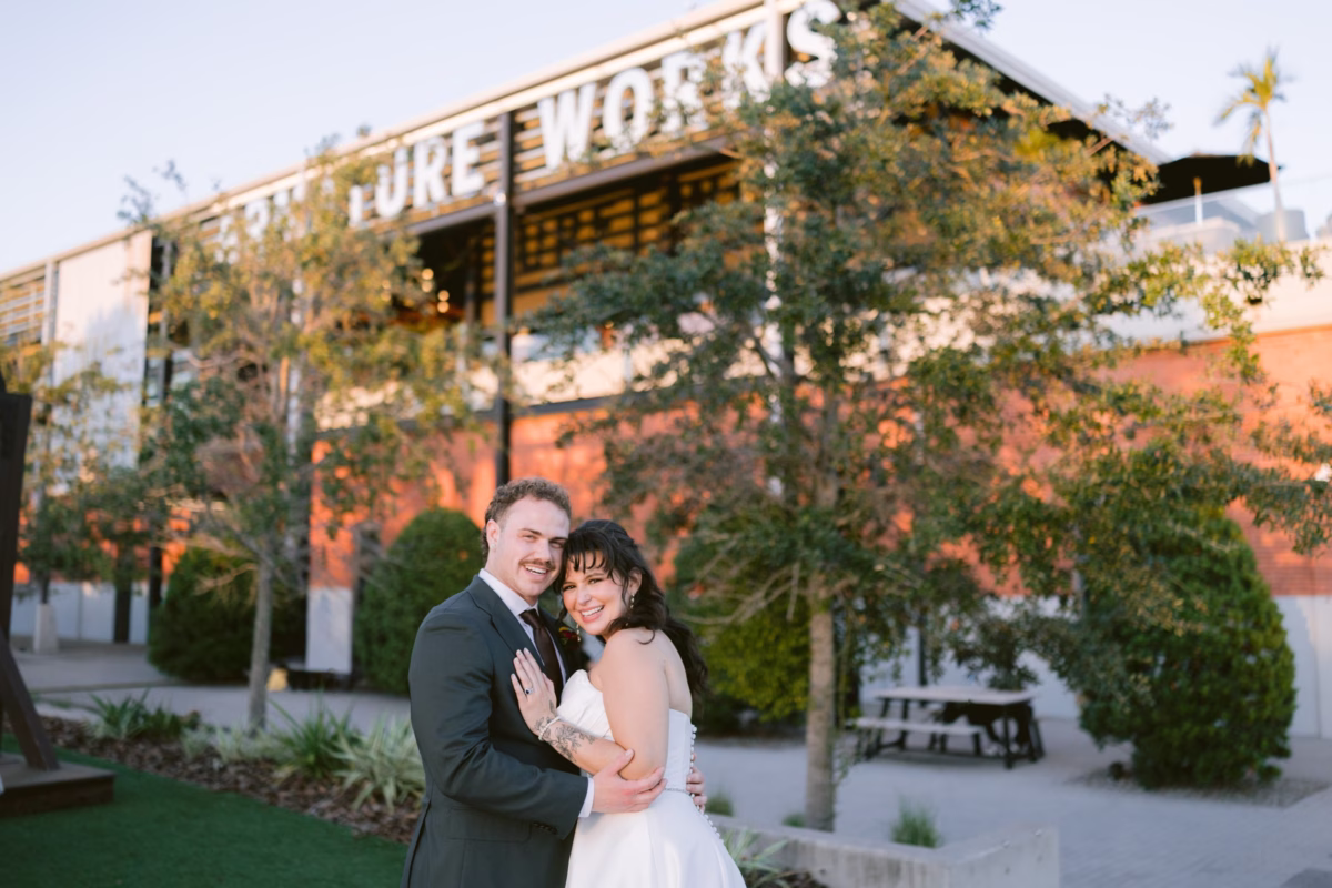 Bride and groom embracing at sunset outside Armature Works in Tampa photographed by Ashley Izquierdo Photography