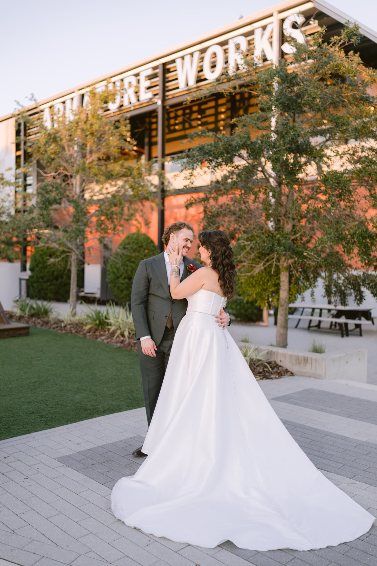 Bride and groom sharing an intimate moment at Armature Works wedding venue in Tampa with industrial building backdrop