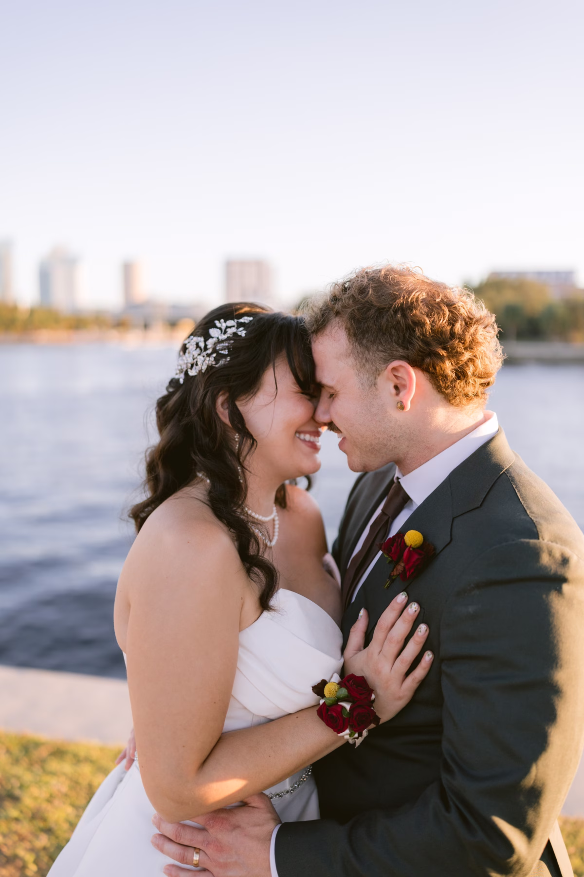Bride and groom embracing at waterfront Armature Works wedding in Tampa with Events in Bloom red boutonniere and corsage