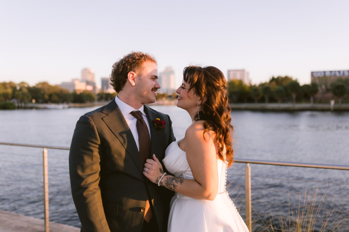 Bride and groom embrace during golden hour wedding portraits at Armature Works waterfront venue in Tampa