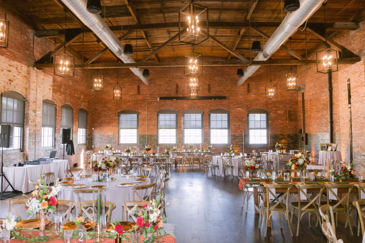 Industrial wedding reception with exposed brick walls and elegant floral centerpieces by Events in Bloom at Armature Works in Tampa