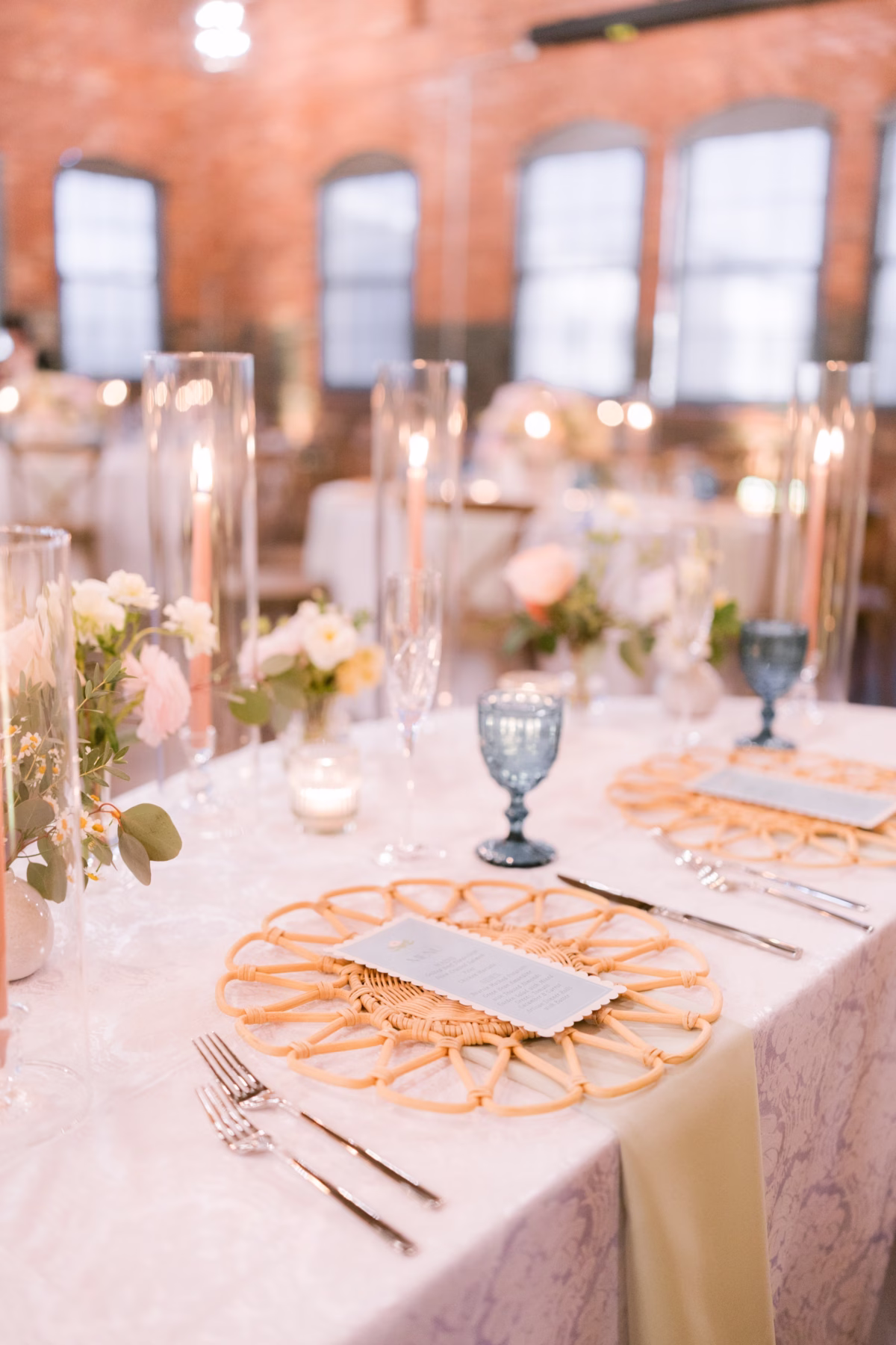 Elegant wedding reception tablescape with woven charger plates, blue goblets, and floral centerpieces by I Dew Events at Armature Works Tampa