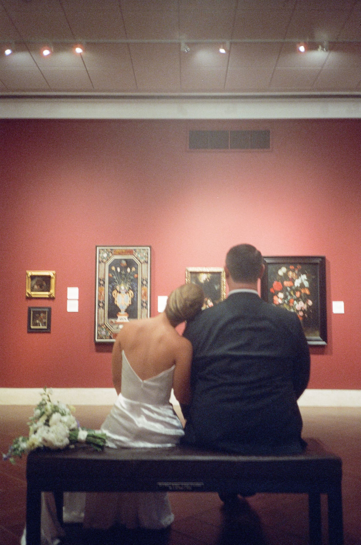 Bride and groom sitting together viewing artwork at Nancy Cotto Events art museum wedding venue with Wonderland Floral Art bridal bouquet in St. Petersburg