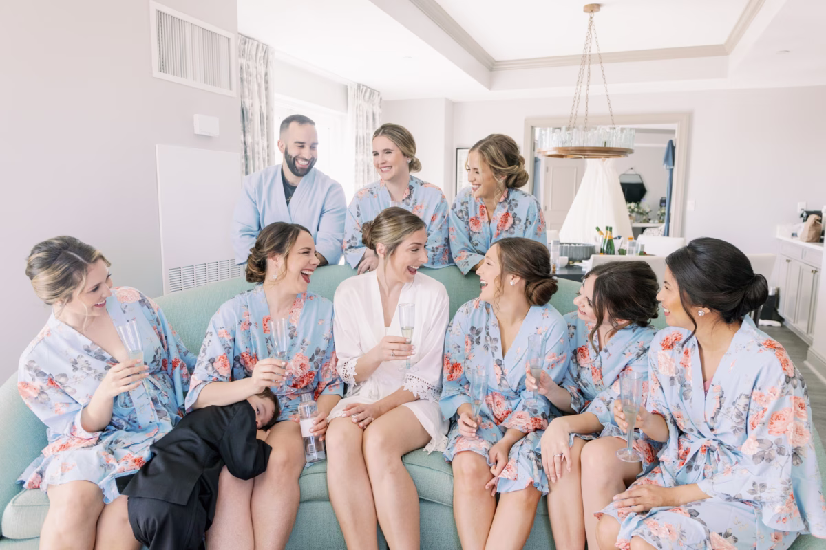 Bride in white robe with bridesmaids in floral robes getting ready at The Vinoy St. Petersburg with hair and makeup by Femme Akoi