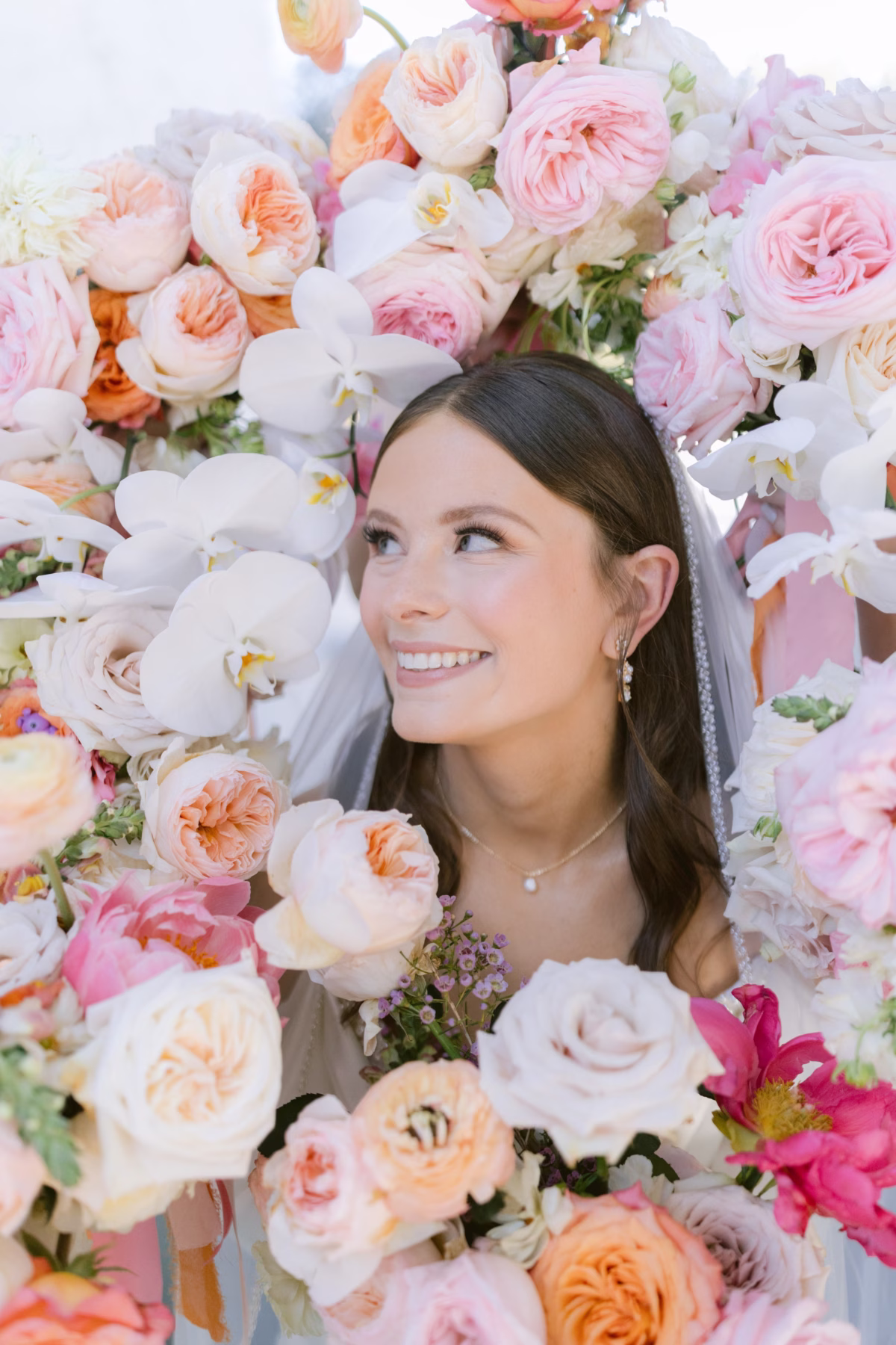 Bride smiling surrounded by elaborate pink and peach floral installation by Golden Wild Florals at Soire Estate Tampa garden wedding