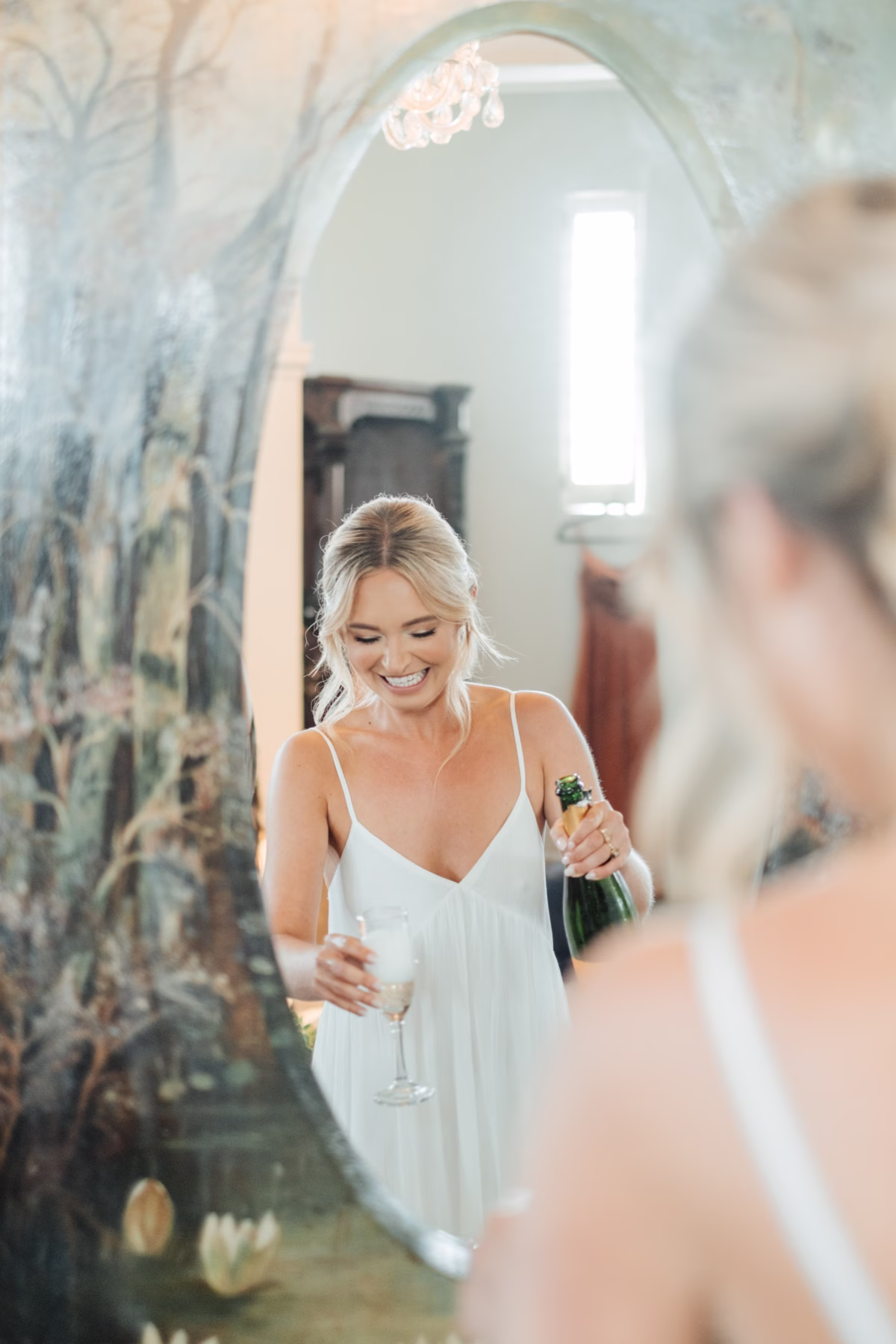 Bride in Alexandra Grecco wedding dress pouring champagne during wedding celebration at The Lightner Museum in St. Augustine photographed by Ashley Izquierdo Photography