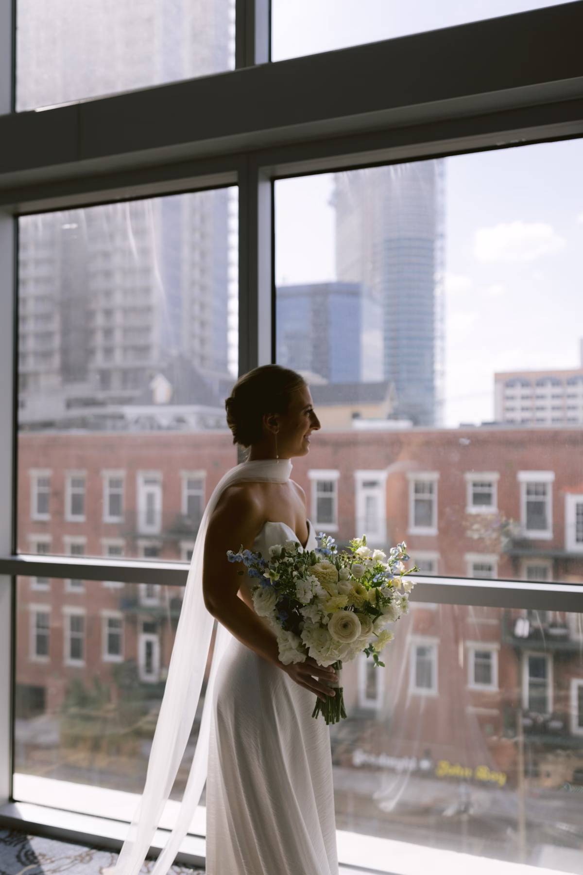 Bride in wedding dress holding white and blue floral bouquet by Wonderland Floral Art at Nancy Cotto Events venue in St. Petersburg