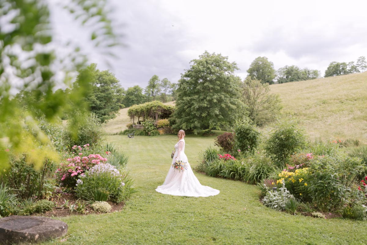 Bride in Maggie Sottero gown holding Cherry Brandy Designs bouquet in garden at Red Maple Vineyard wedding photographed by Tampa Bay wedding photographer Ashley Izquierdo
