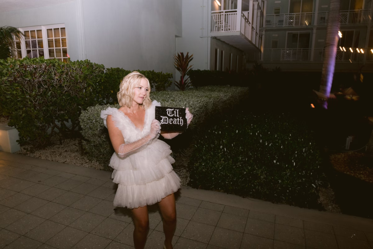 Bride in white tulle dress holds til death sign at Casa Marina Key West wedding photographed by Ashley Izquierdo Photography