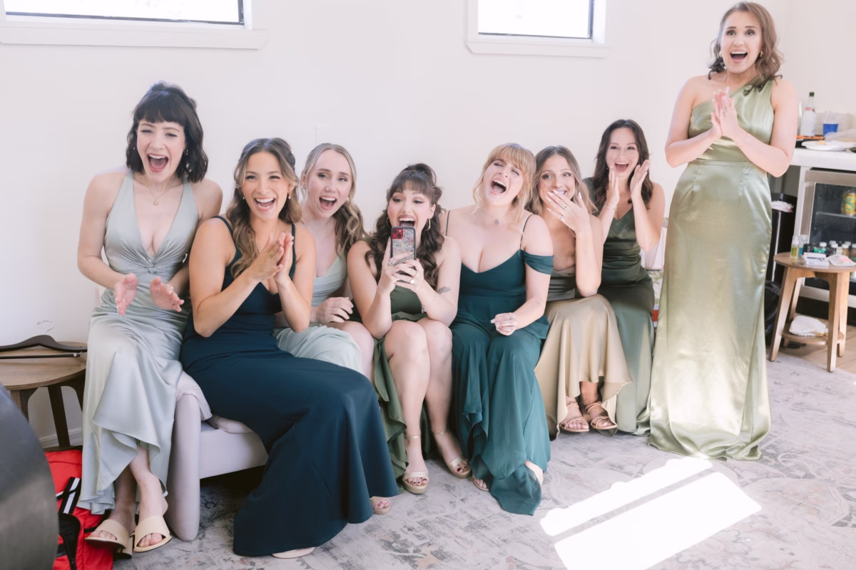 Bridesmaids in sage green and teal dresses react excitedly while getting ready at Soire Estate Tampa wedding photographed by Ashley Izquierdo Photography