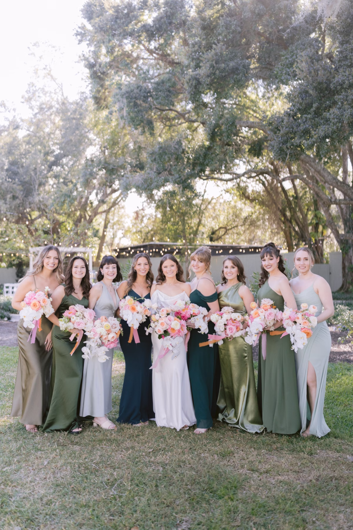 Bridesmaids in green and neutral dresses holding pink and white bouquets by Golden Wild Florals at Soire Estate Tampa garden wedding