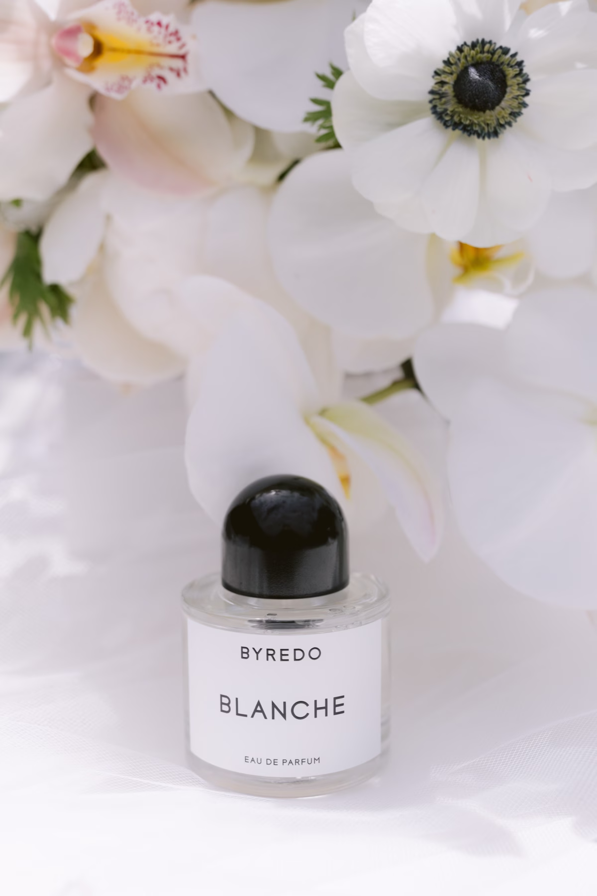 Byredo Blanche perfume bottle styled with white anemone and orchid flowers for Hudson Valley wedding at The Roundhouse Beacon by florist Maky The Diva Flowers
