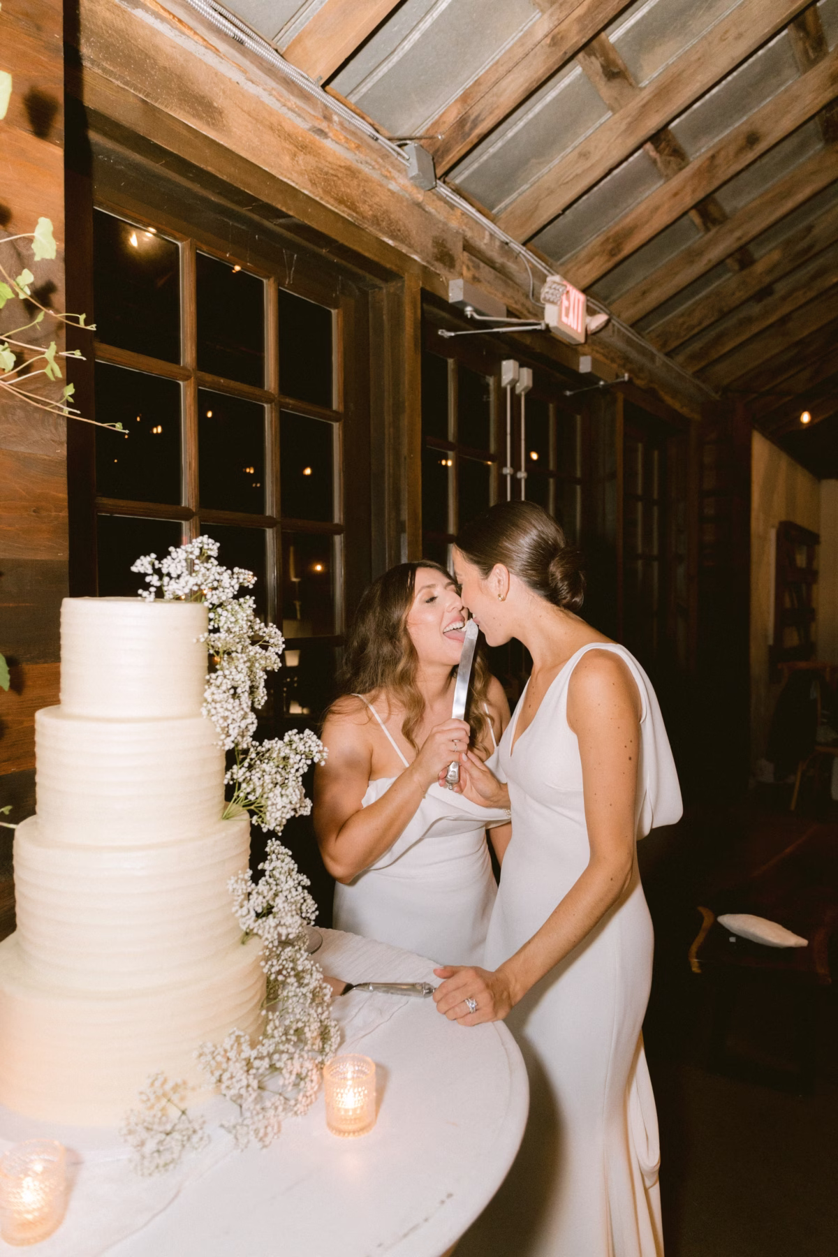 cake cutting ceremony johnsons locust hall farm wedding new jersey - A Farm Wedding at Johnson's Locust Hall, New Jersey Two brides in white dresses cutting their wedding cake decorated with baby's breath flowers at Johnson's Locust Hall farm wedding venue in New Jersey