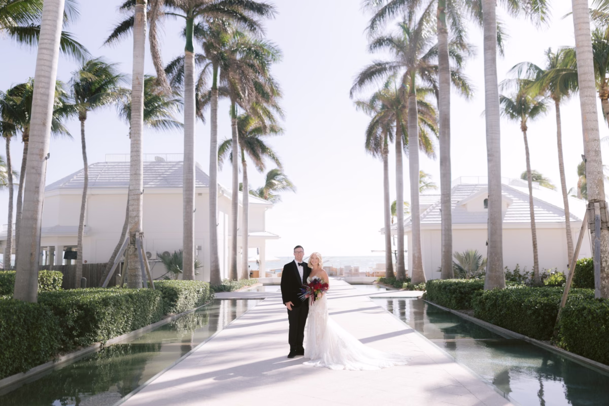 Bride and groom walking down palm tree lined walkway at Casa Marina Key West wedding venue