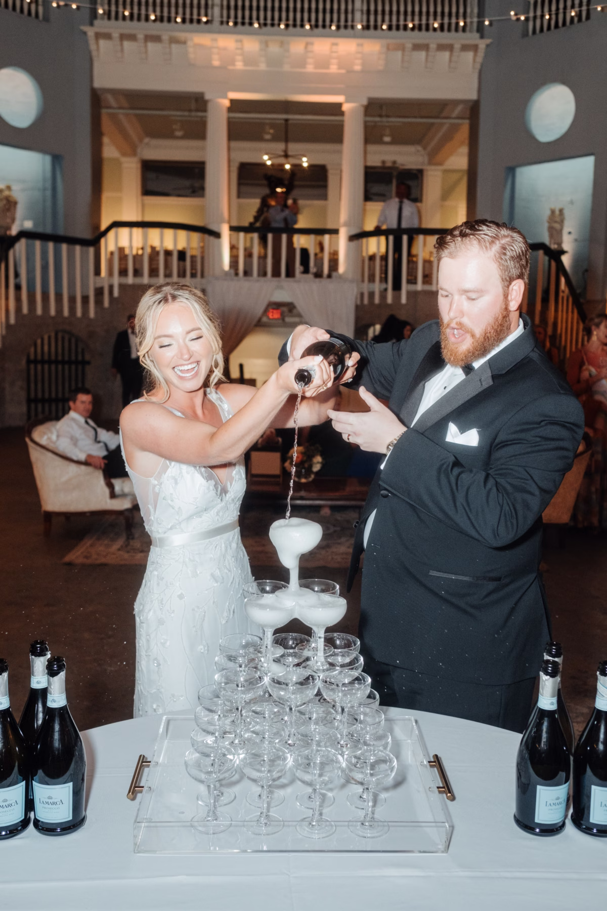 Bride and groom pouring champagne tower at historic Lightner Museum wedding reception planned by Coastal Celebrations in St Augustine