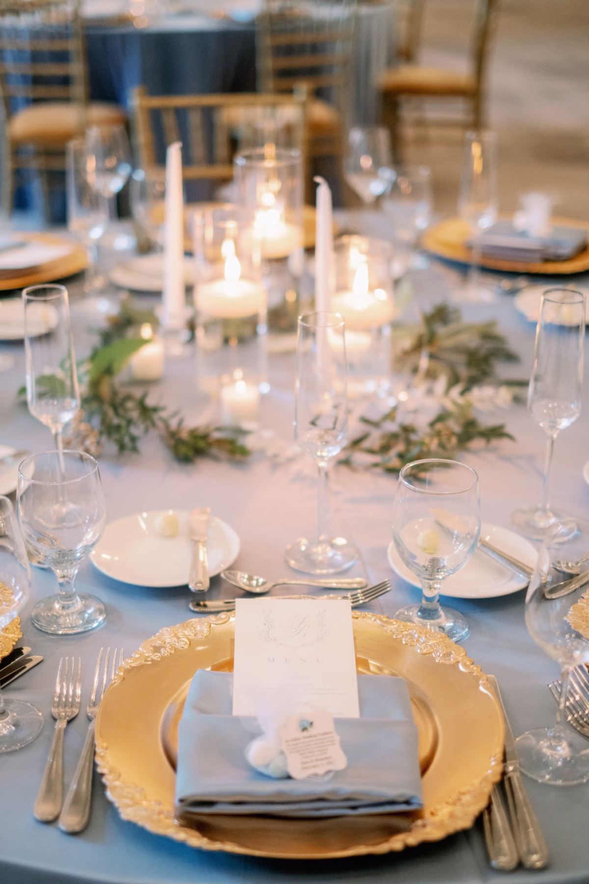 Elegant wedding reception table setting with gold charger plates, candles and greenery at The Vinoy St. Petersburg planned by Lemon Drops Weddings and Events