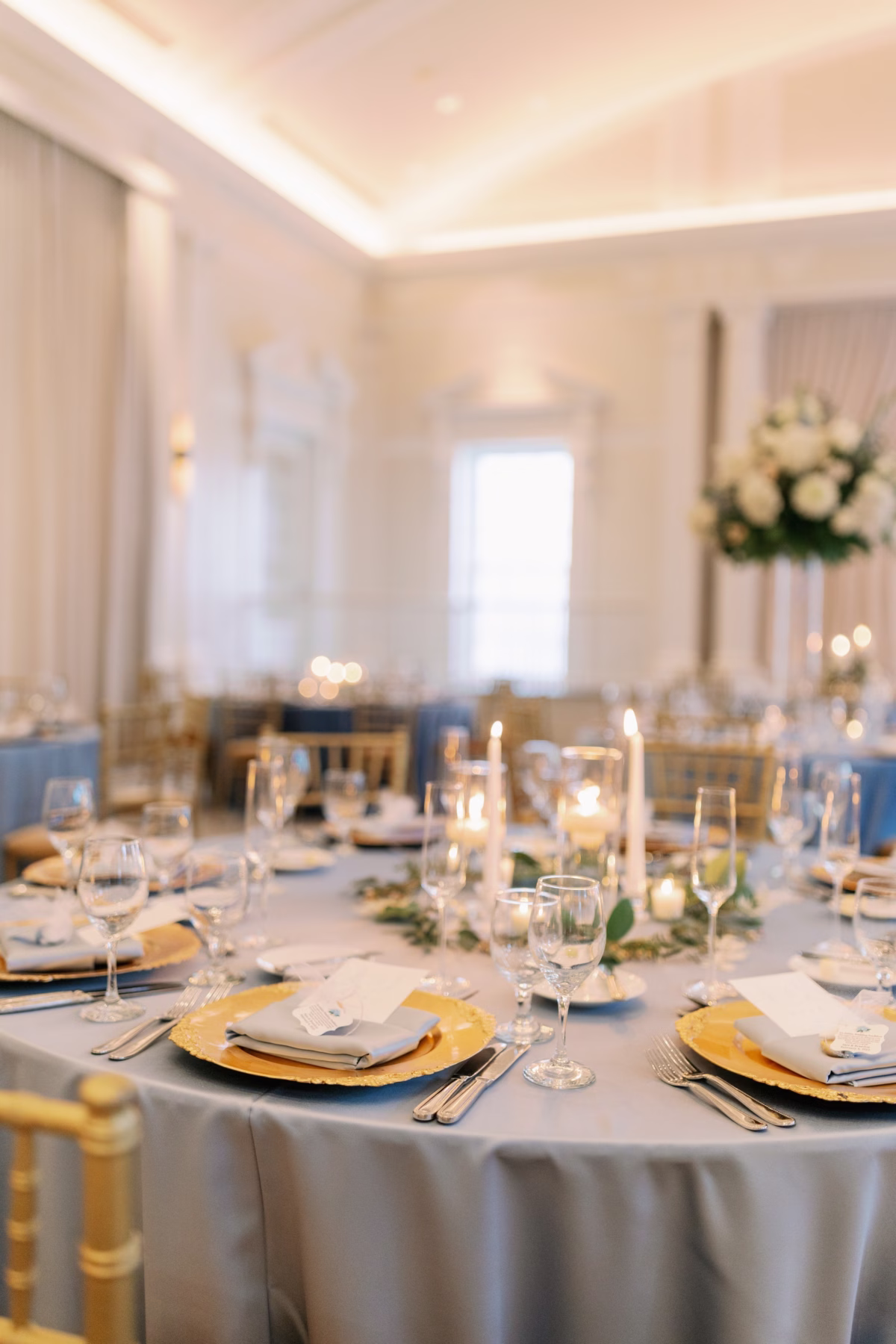 Elegant wedding reception tablescape with gold chargers, candles and greenery by Lemon Drops Weddings and Events at The Vinoy St. Petersburg