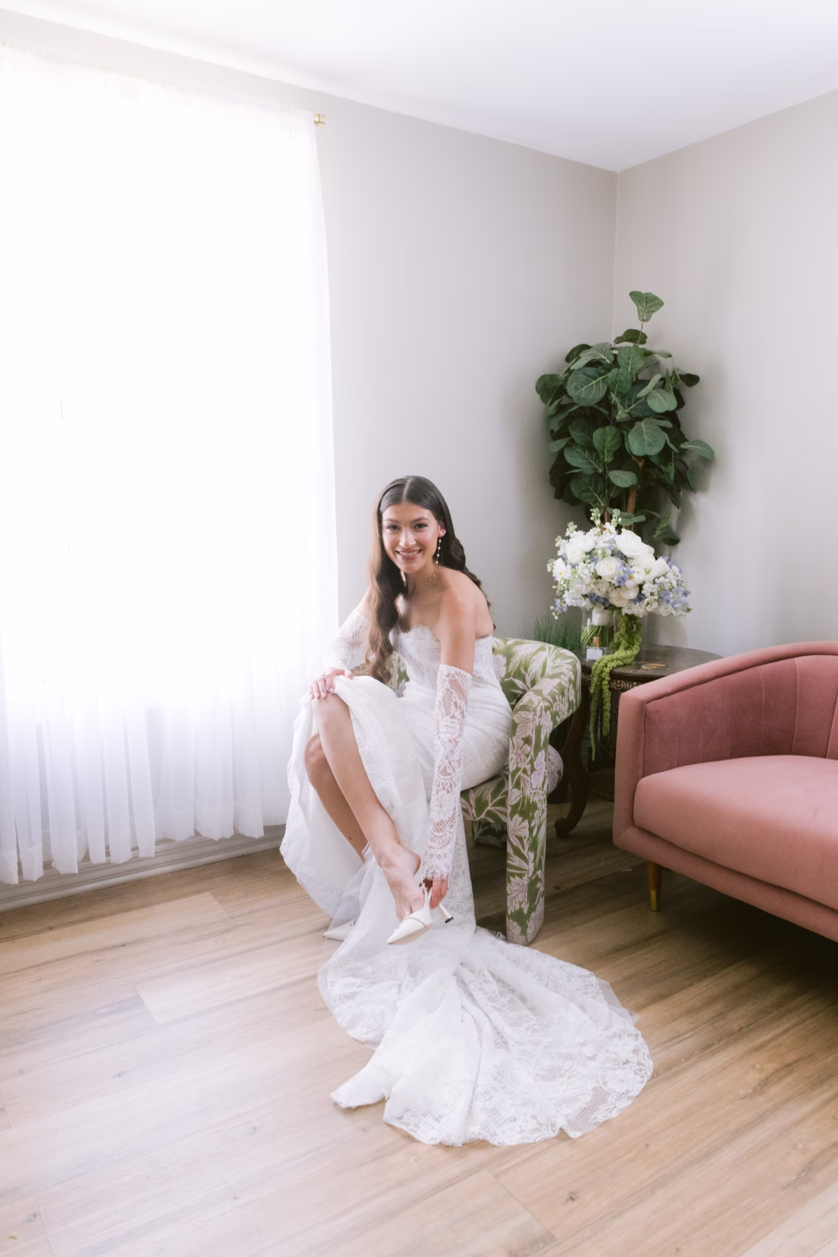 Bride in elegant white lace wedding dress by Ella Blu Bridal sitting in modern bridal suite at Soire Estate Tampa wedding venue