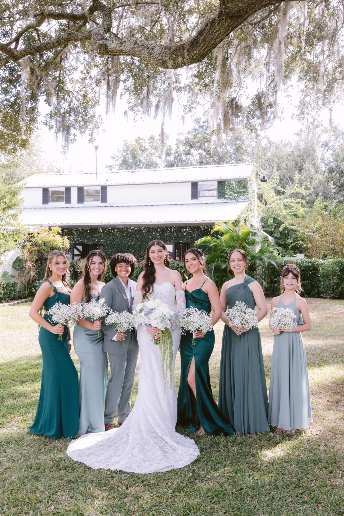Bride in white gown with emerald and sage green bridesmaids holding baby's breath bouquets by Ava Elise Decor at Soire Estate Tampa wedding