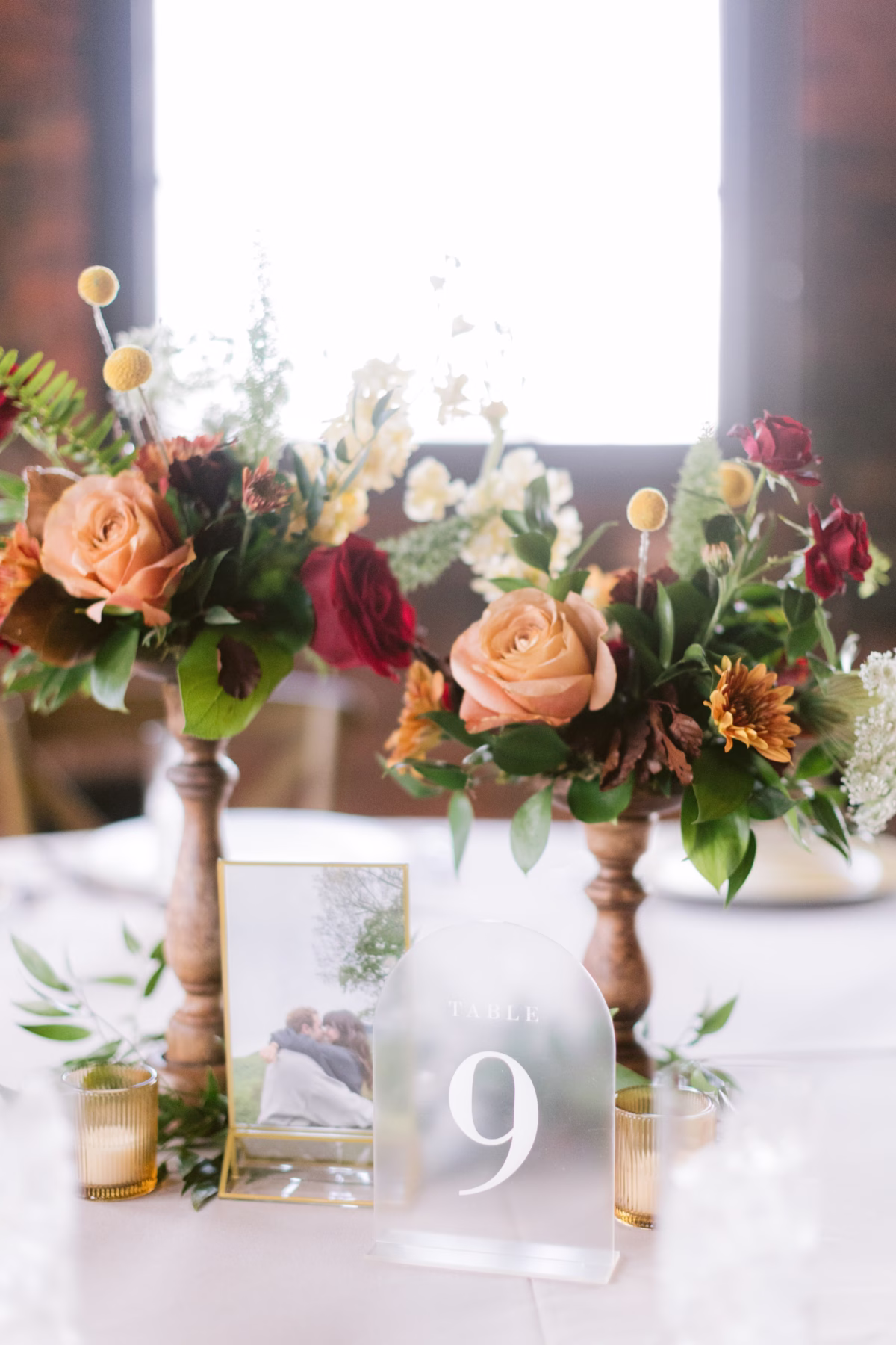 Elegant floral centerpieces with peach roses and burgundy flowers by Events in Bloom at Armature Works Tampa wedding photographed by Ashley Izquierdo Photography