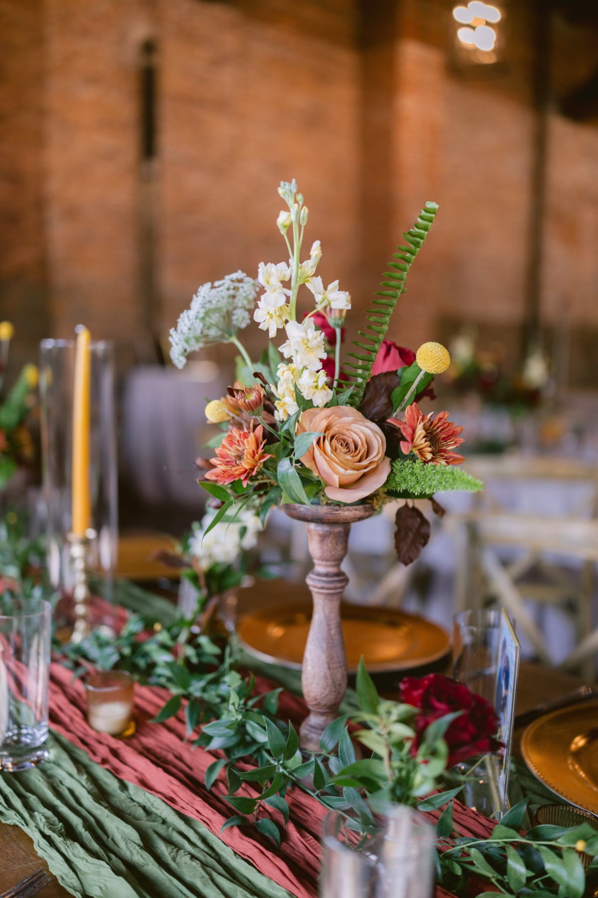 Elegant wedding centerpiece by Events in Bloom featuring coral roses and autumn florals on wooden pedestal at Armature Works Tampa