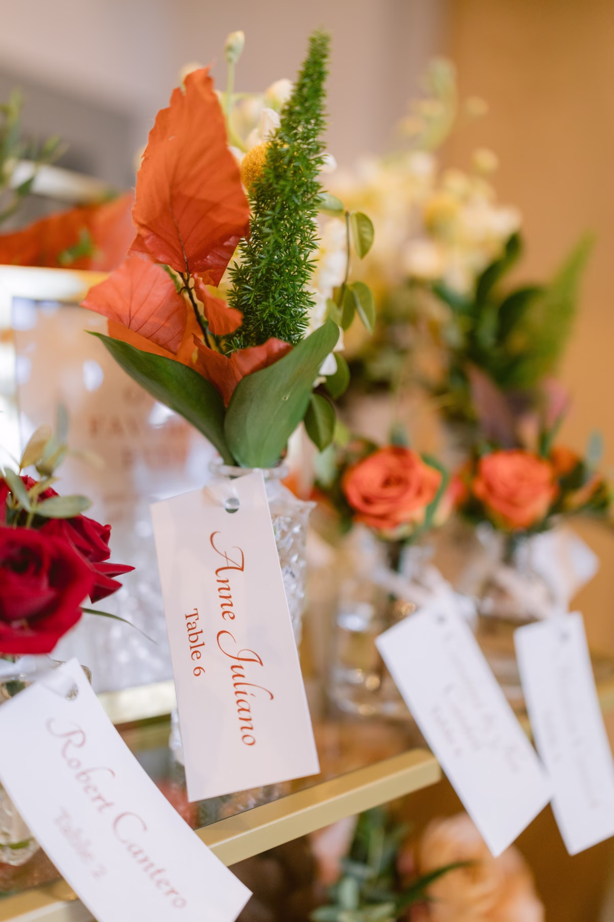 Wedding escort cards with orange and red floral arrangements by Events in Bloom at Armature Works Tampa