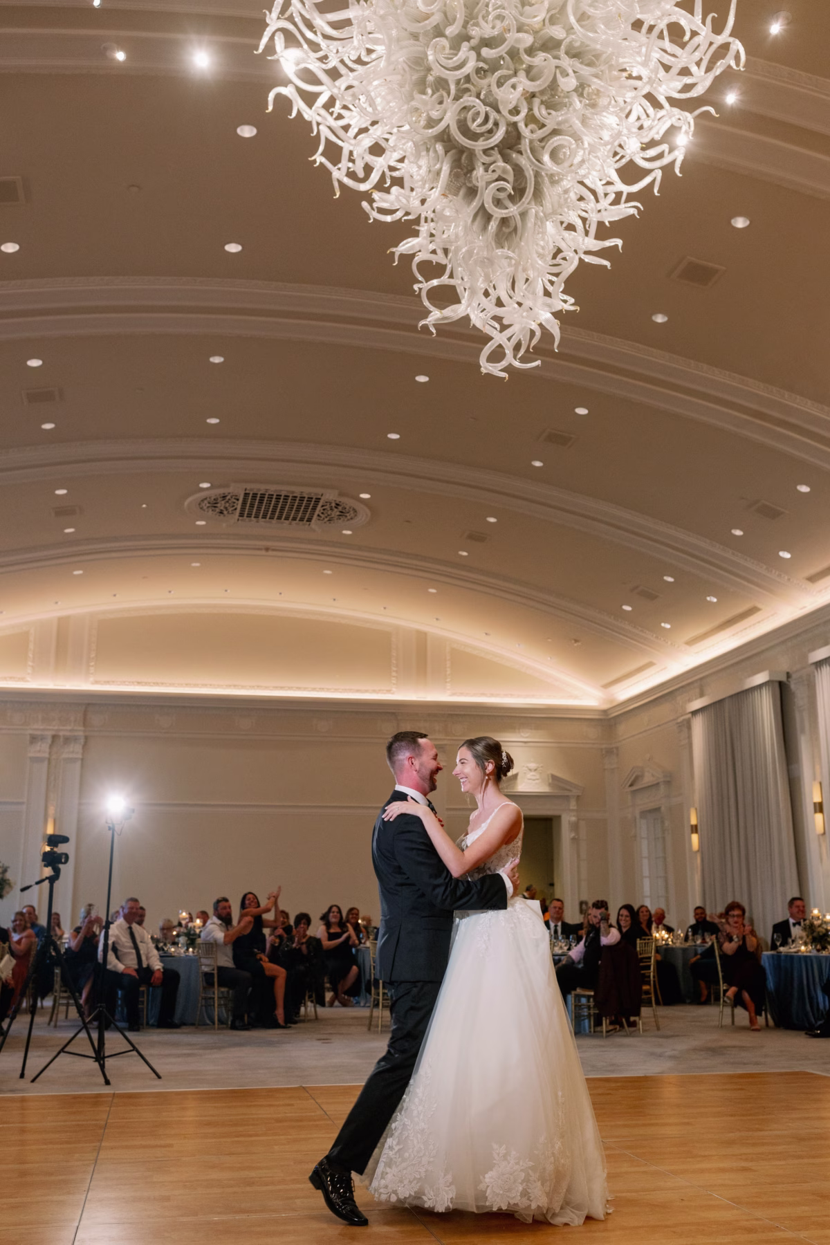 Bride and groom share their first dance under an elegant white chandelier at The Vinoy St. Petersburg wedding planned by Lemon Drops Weddings and Events